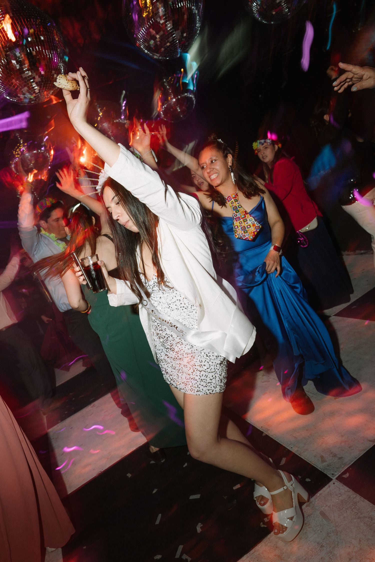 People dancing energetically under colorful disco lights at a party.