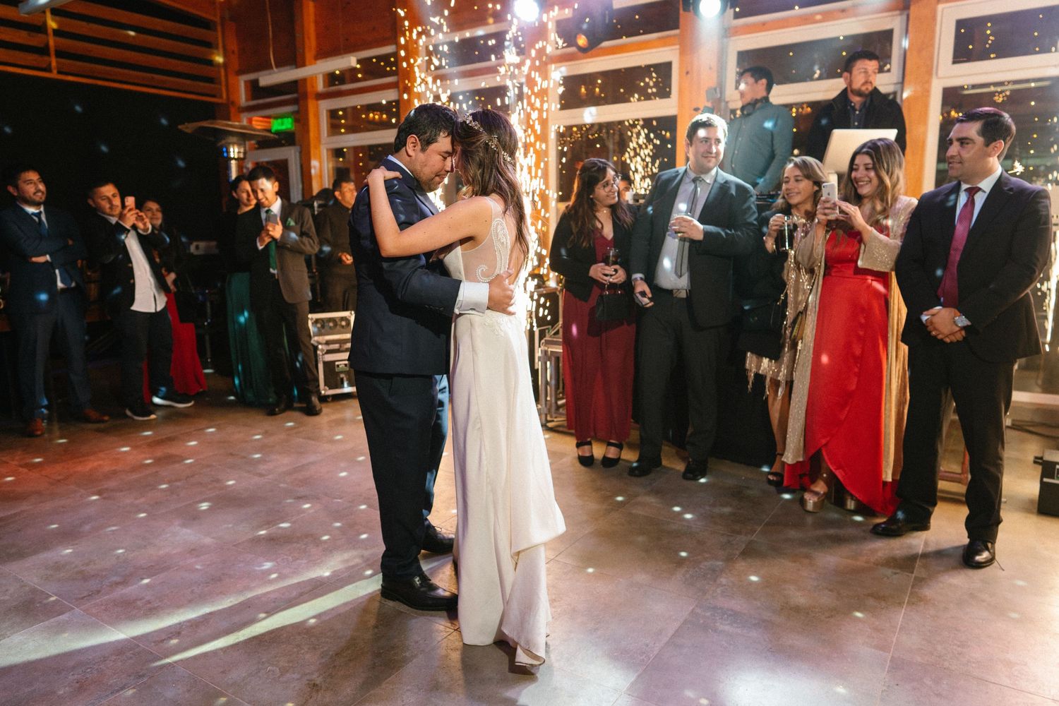 Newlyweds sharing an intimate dance moment while guests watch from the edges of the dance floor.