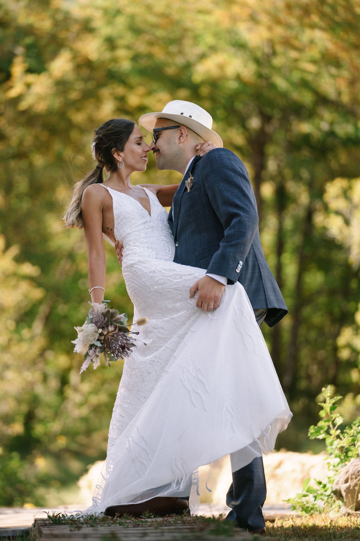 A romantic wedding portrait captures a couple embracing against a backdrop of autumn foliage.