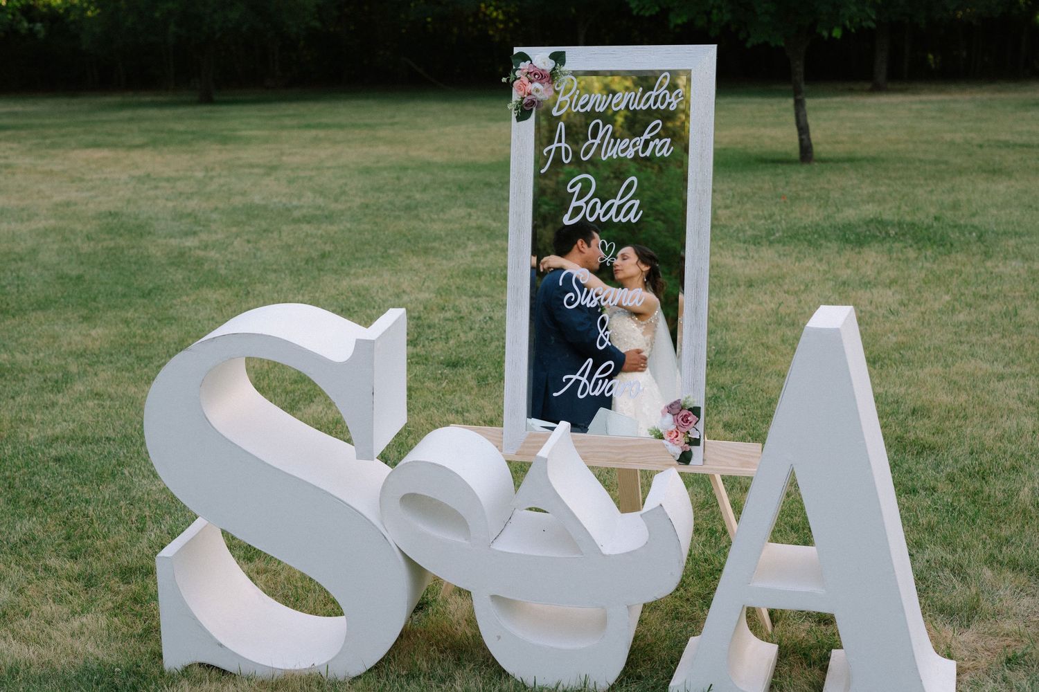 Large white decorative letters S & A displayed on grass at an outdoor wedding venue.