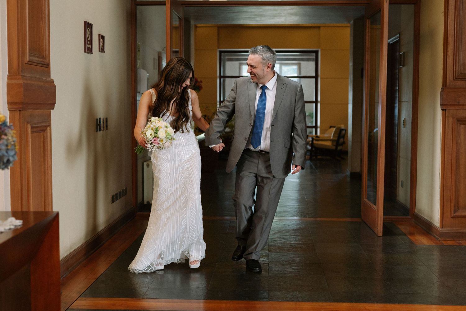 Couple walking together through an elegant hallway with wooden trim.