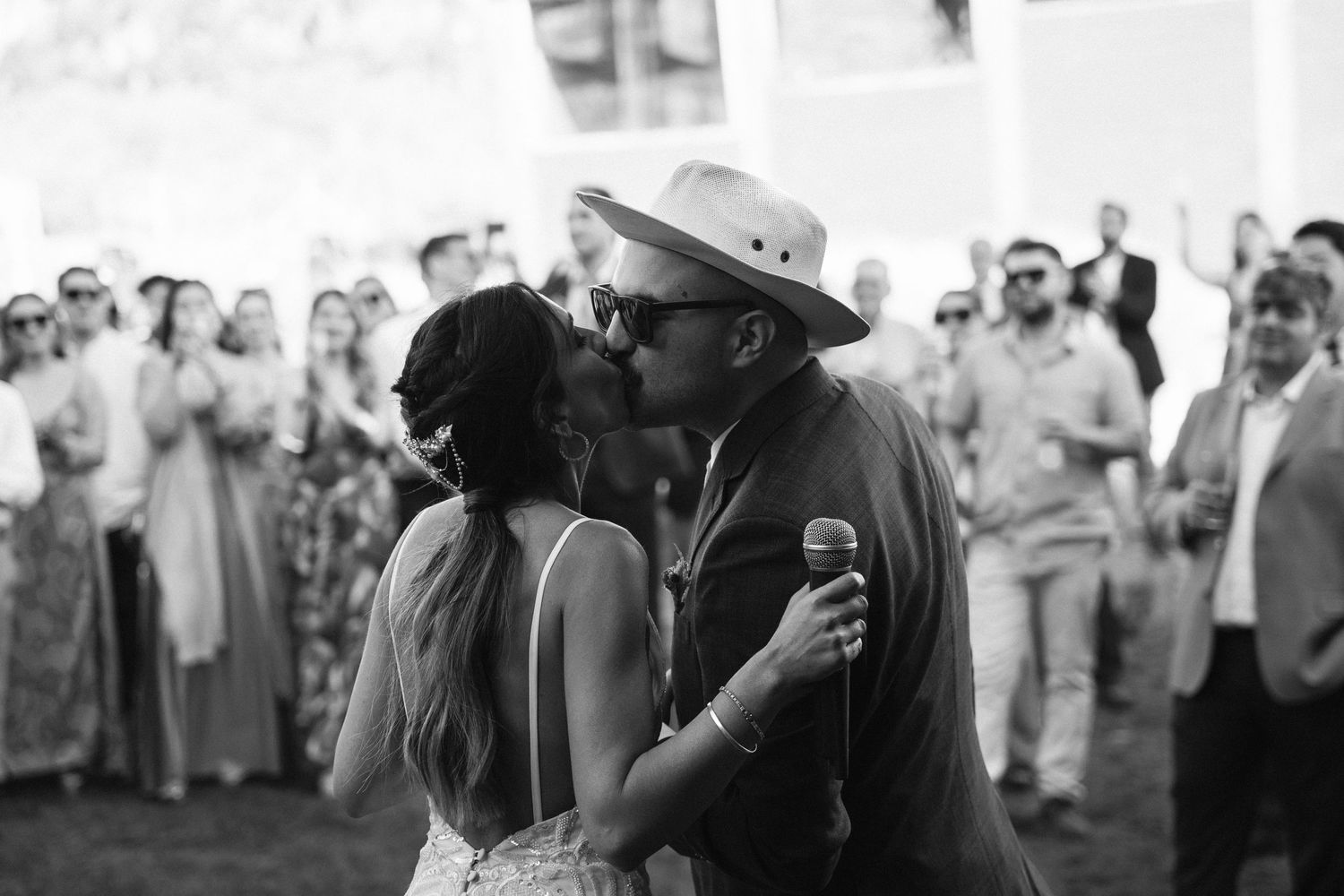 Black and white photo of a tender wedding dance moment surrounded by guests.