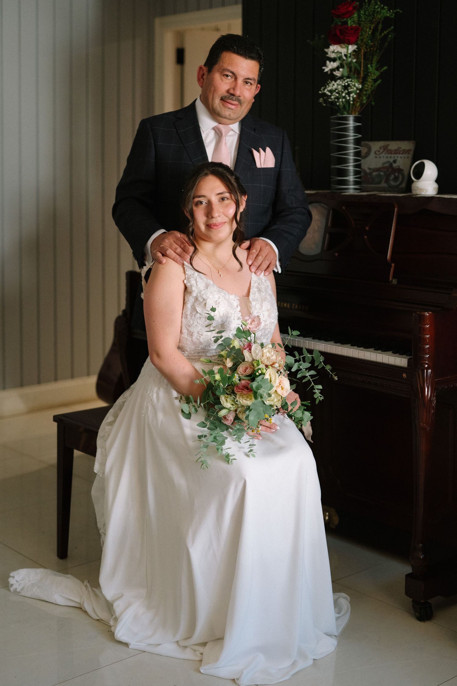Elegant bridal portrait with couple posed by vintage piano.