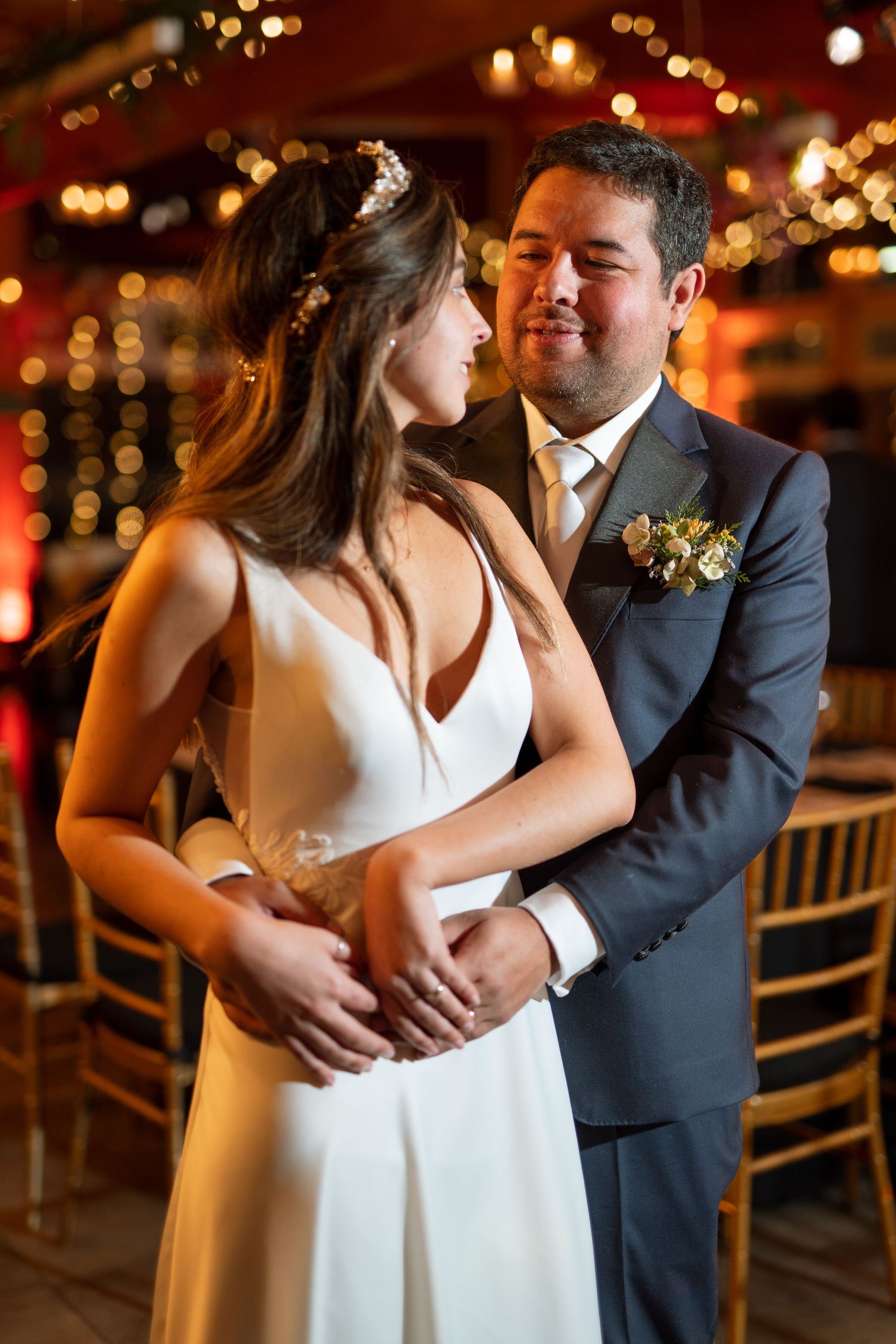 Romantic wedding moment with couple in elegant attire sharing intimate embrace under warm lighting.