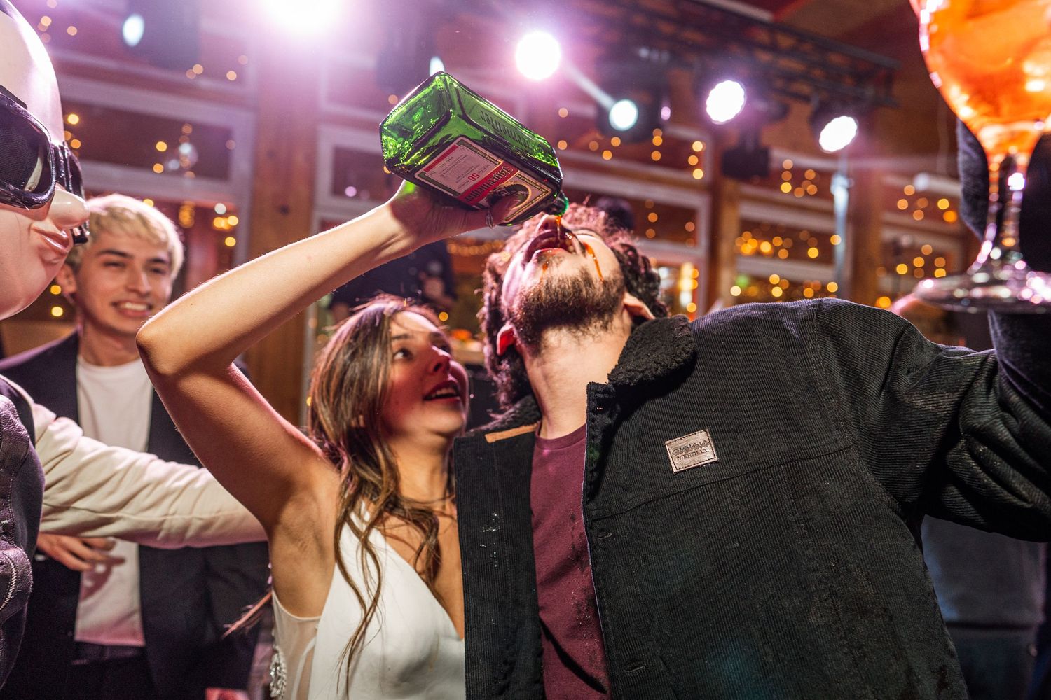 Party goers sharing drinks and celebrating at a nightclub with vibrant lighting.