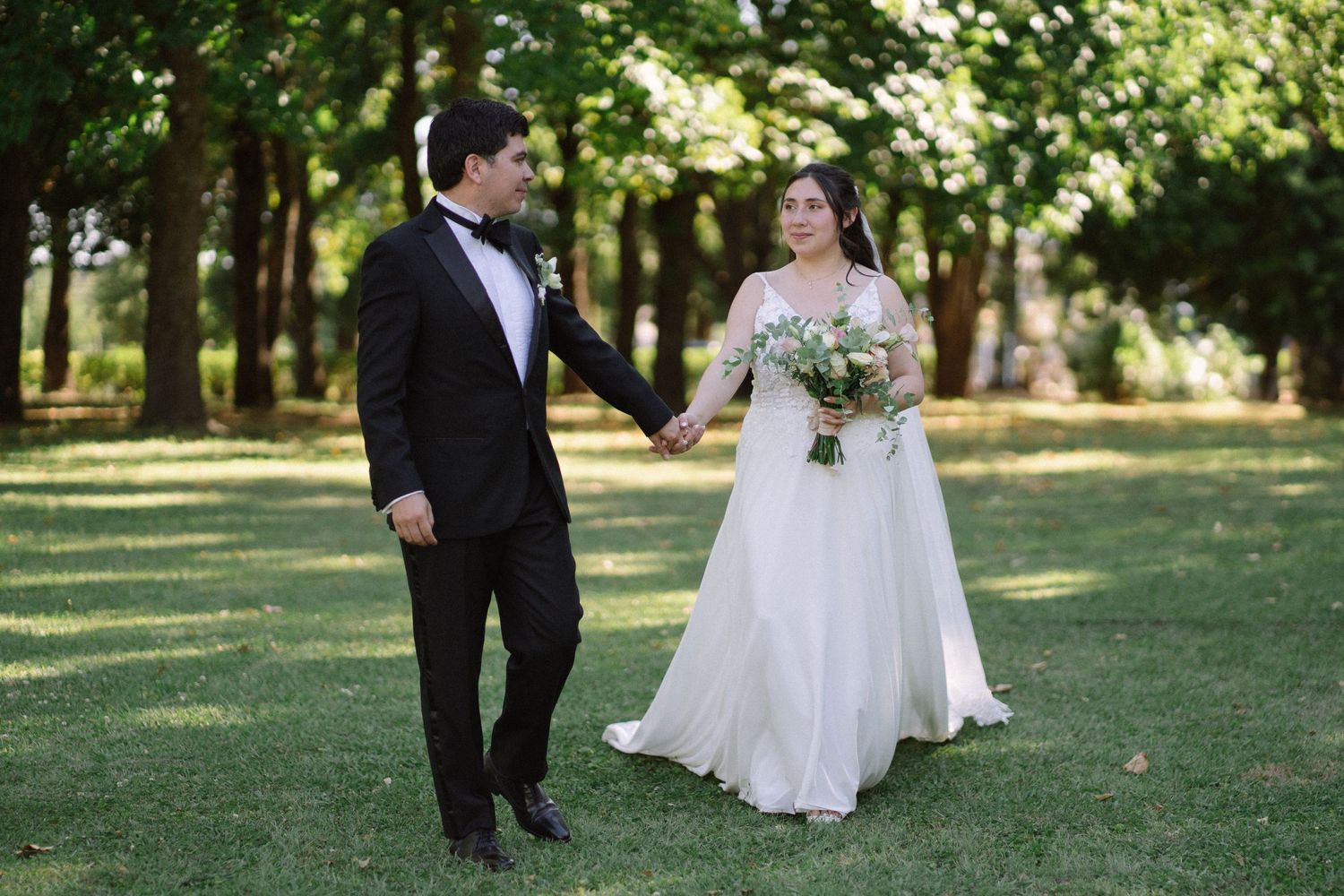 A joyful moment between newlyweds as they dance on their wedding day in a garden setting.