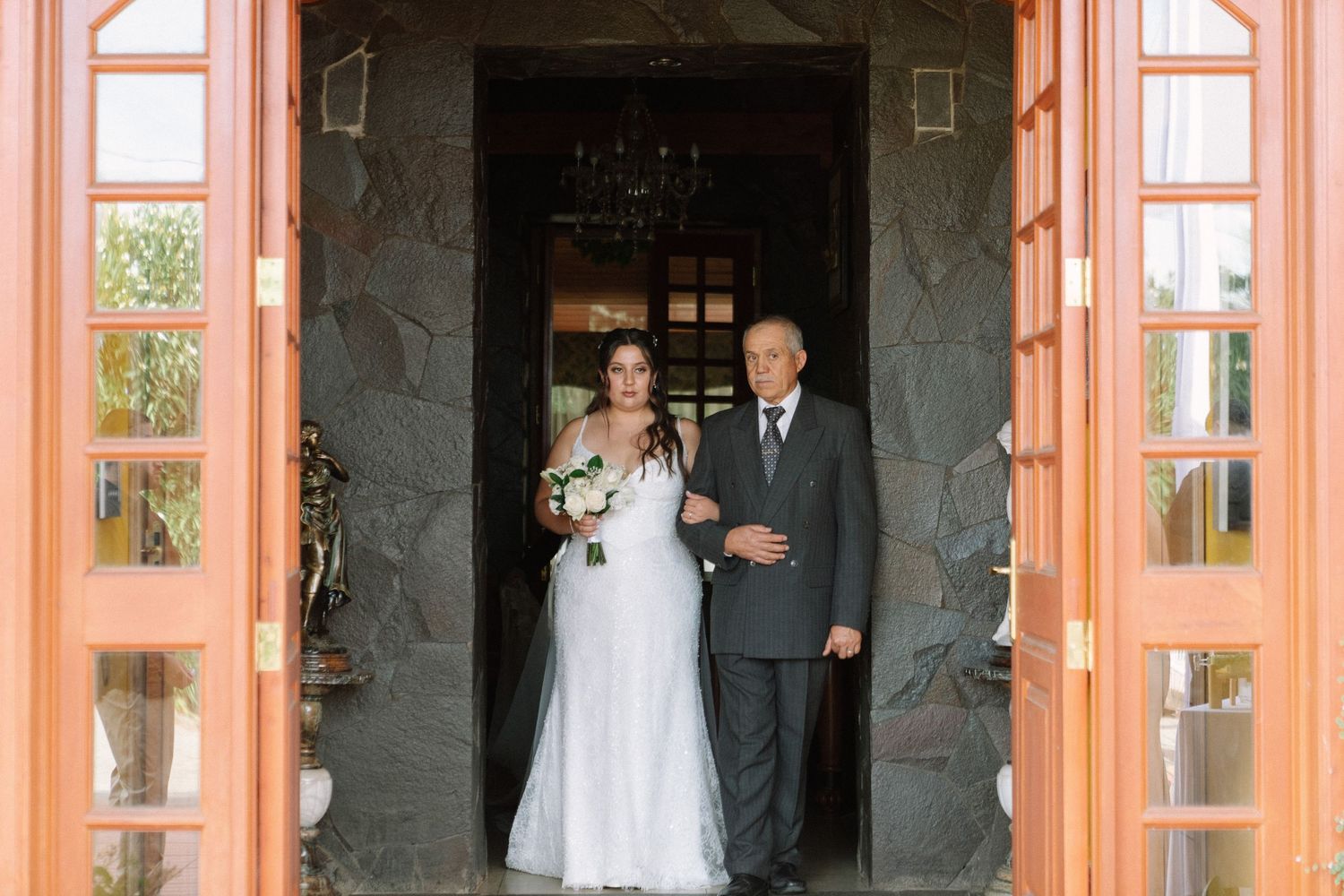 Bride and her escort standing in a stone church doorway before walking down the aisle.