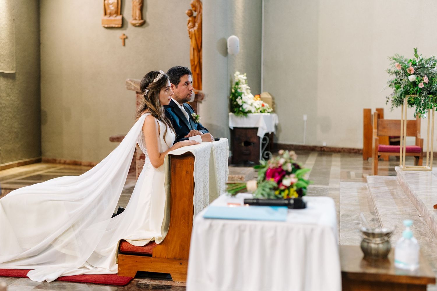 A couple kneels in prayer during their traditional Catholic church wedding.