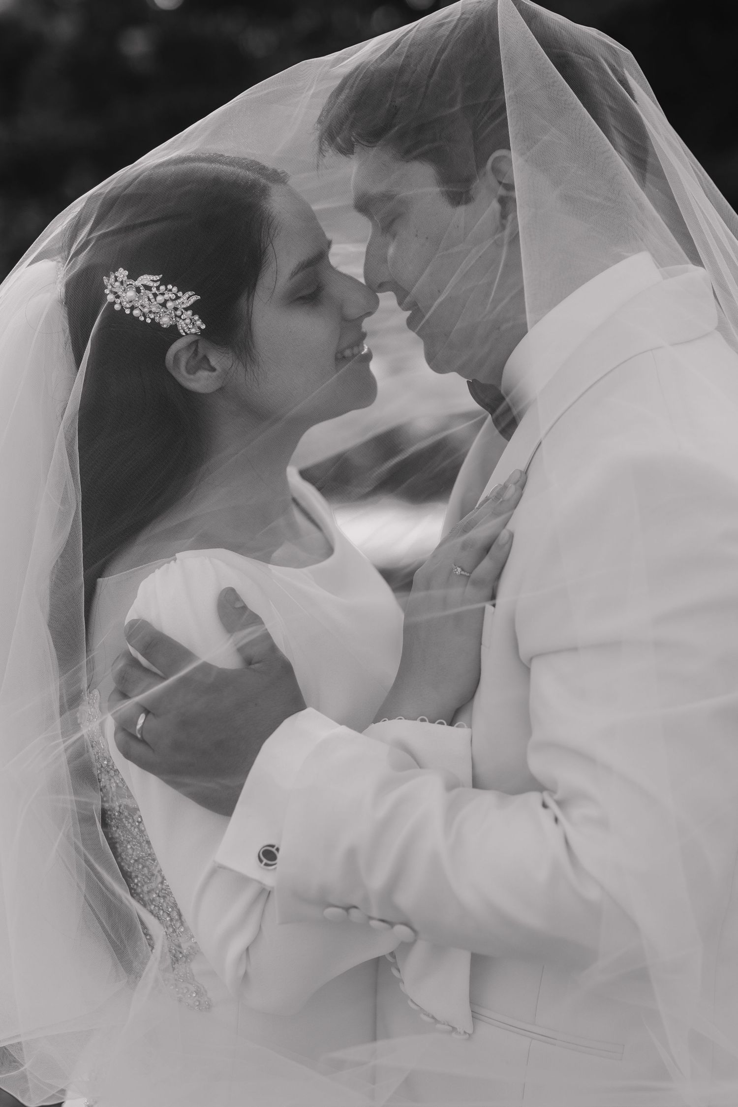 Romantic black and white portrait of a couple under a wedding veil.