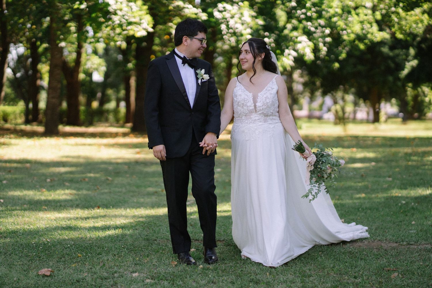 Newlyweds share an intimate moment on their wedding day in a sun-dappled garden setting.