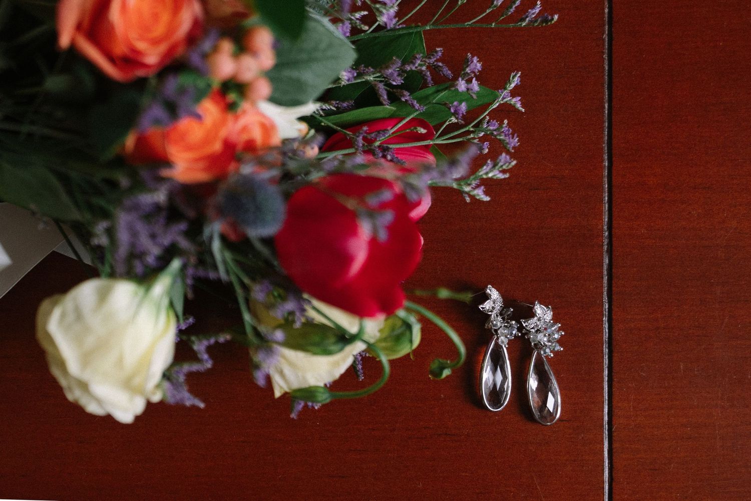Colorful floral arrangements featuring roses and delicate purple flowers displayed on a dark wooden surface.