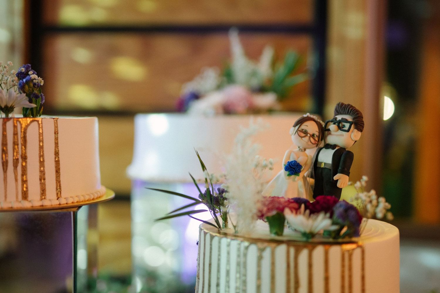 Wedding cake topped with custom figurine decorations and metallic accents.