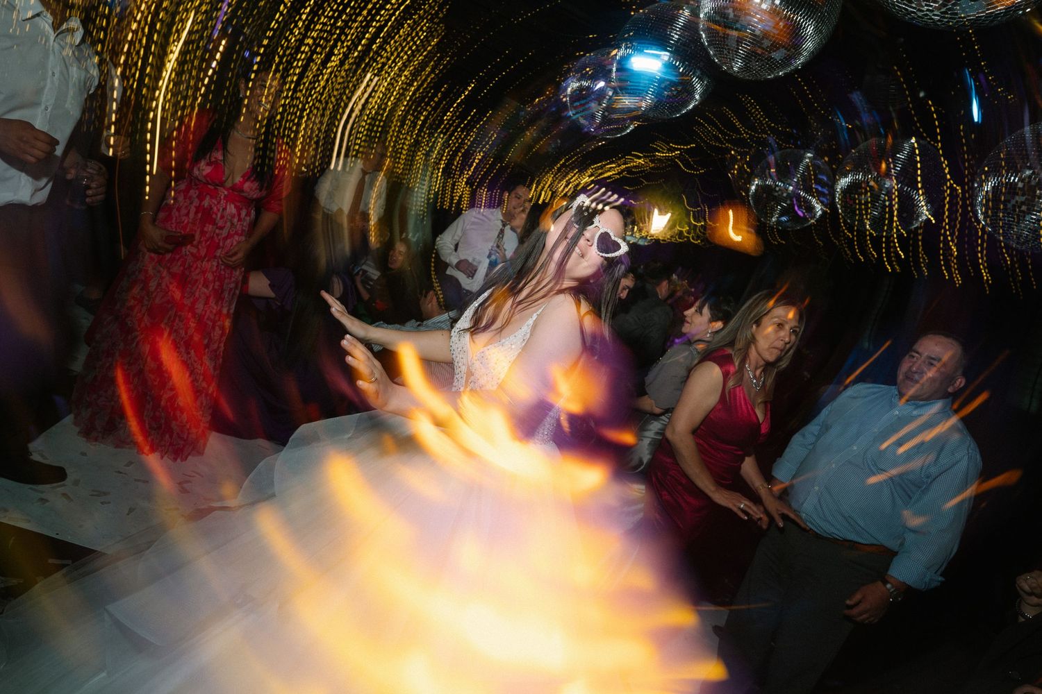 Blurred motion captures dancers in a dimly lit venue with disco lights and glowing effects.