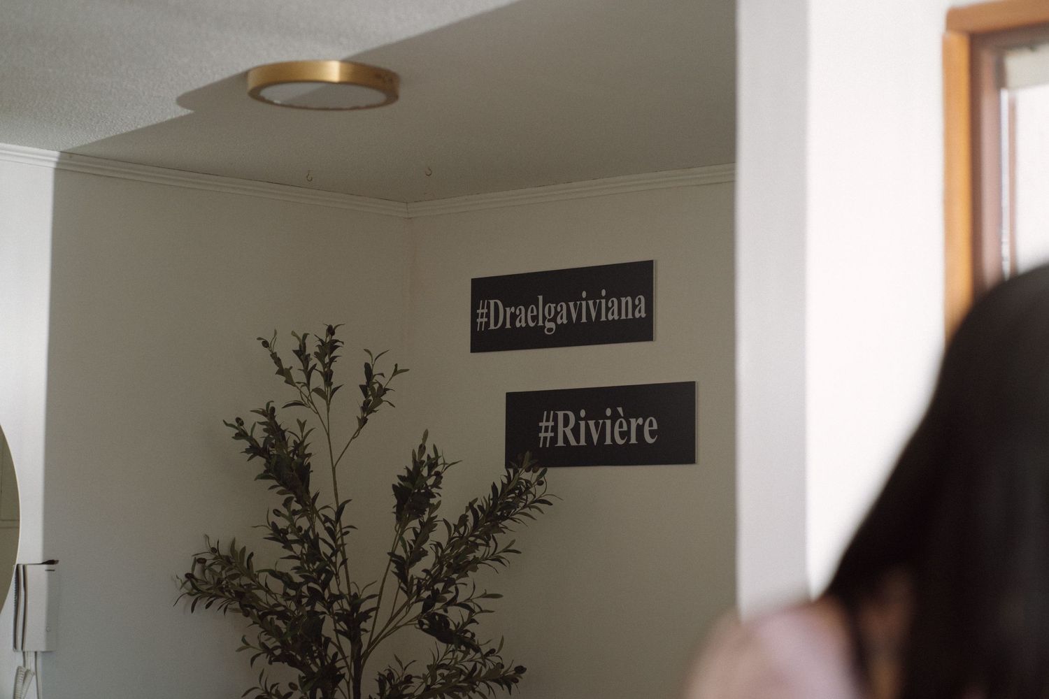 Interior wall with black decorative signs reading 'Designmama' and 'Riviere'.