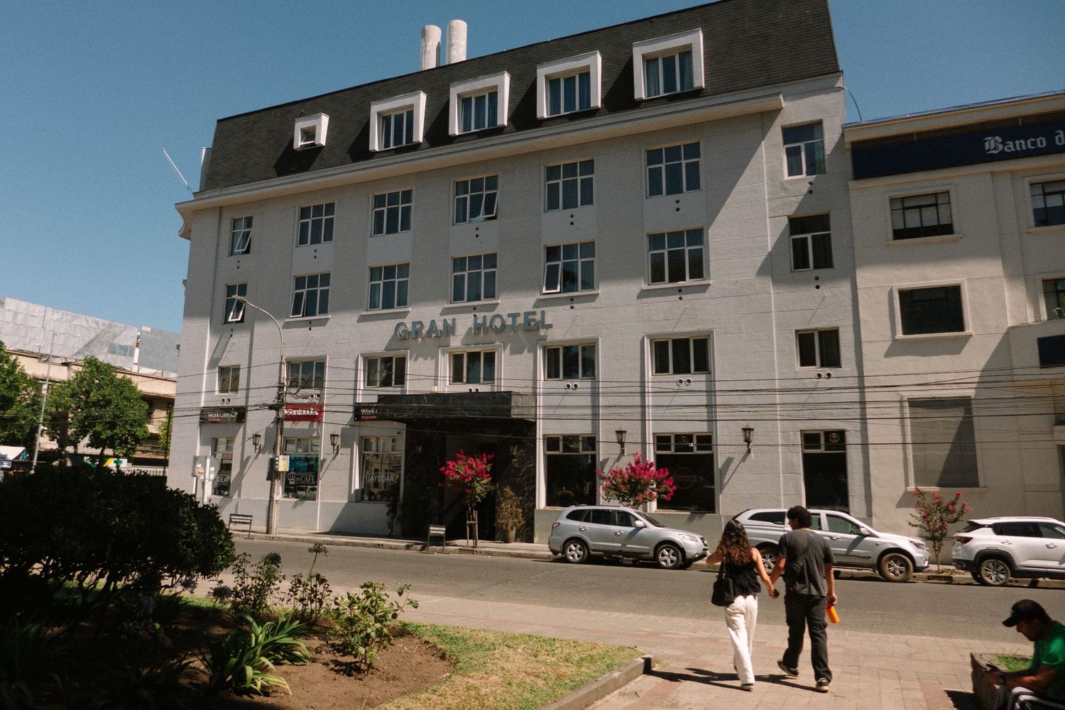 A white multi-story building with colonial architecture on a sunny street.