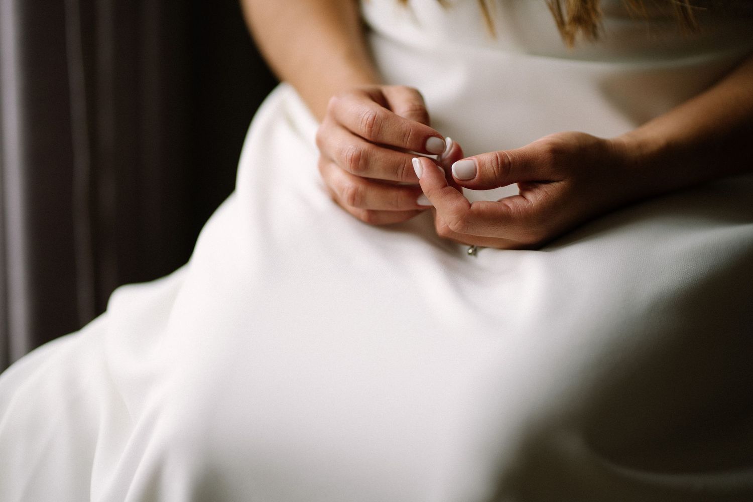 A close-up view of hands holding a white ceramic coffee cup against a blurred background.