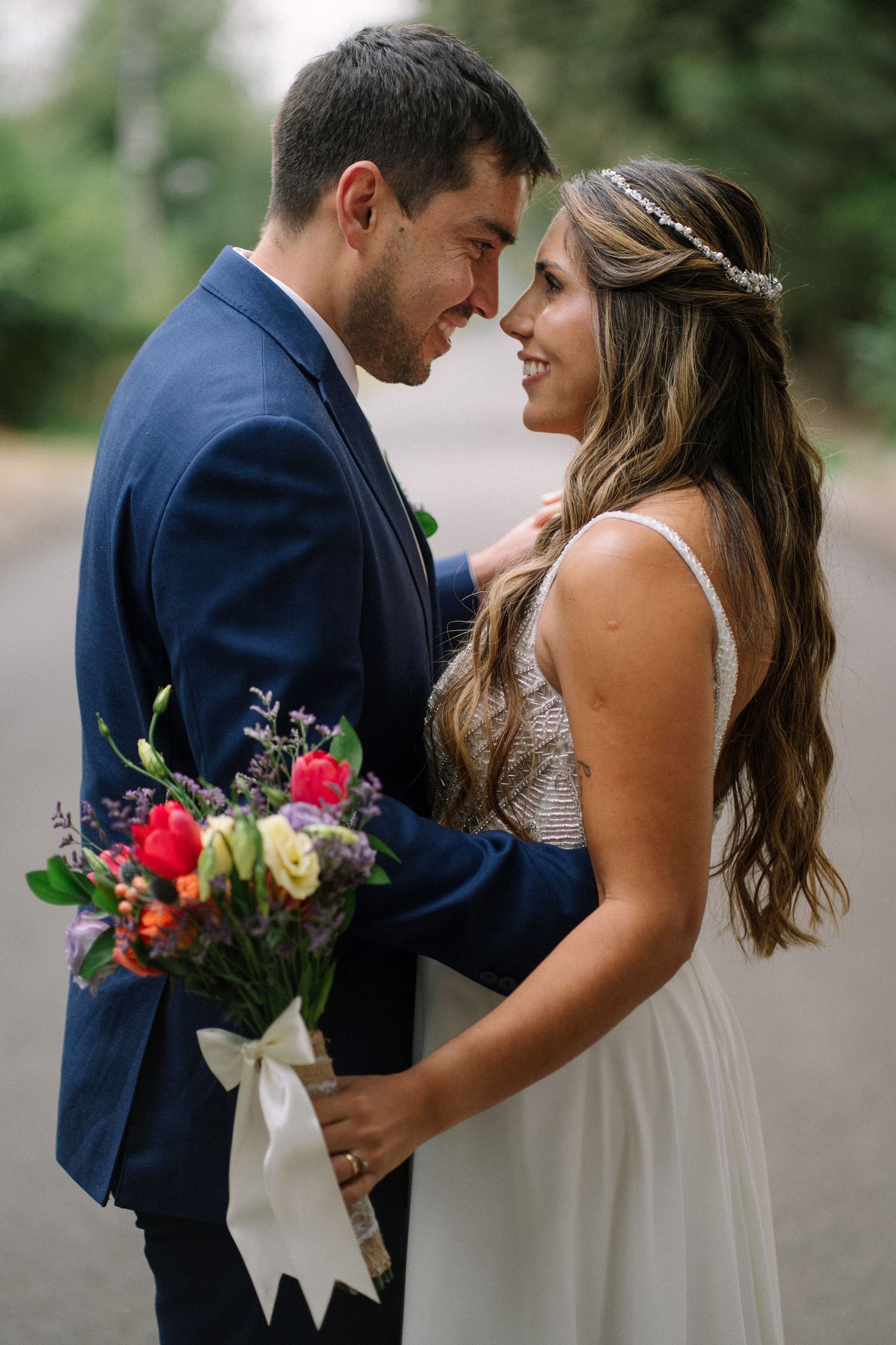 Romantic wedding couple in navy suit and white dress share intimate moments in outdoor portrait series.