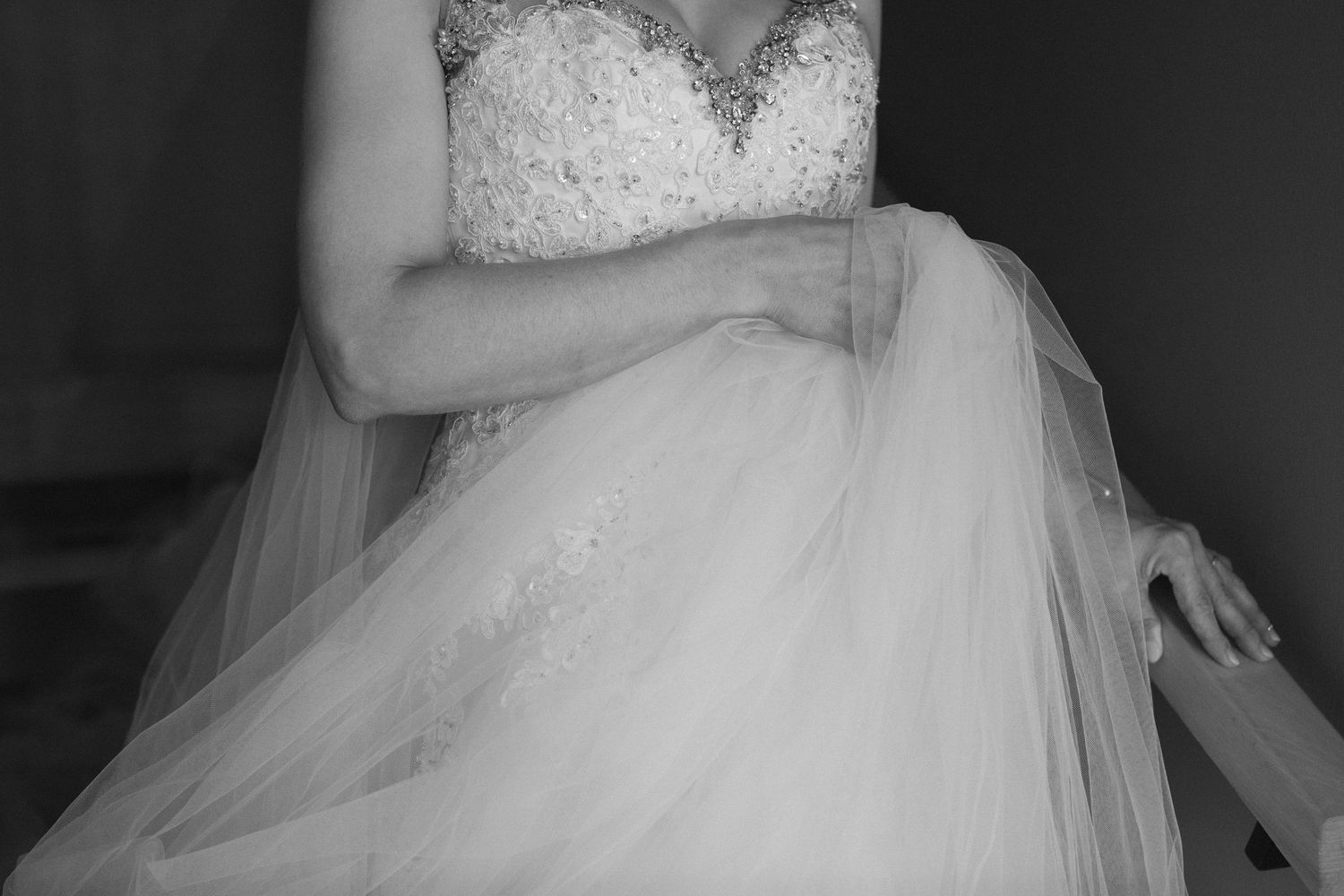 Close-up of bride's white lace wedding dress with flowing tulle skirt.