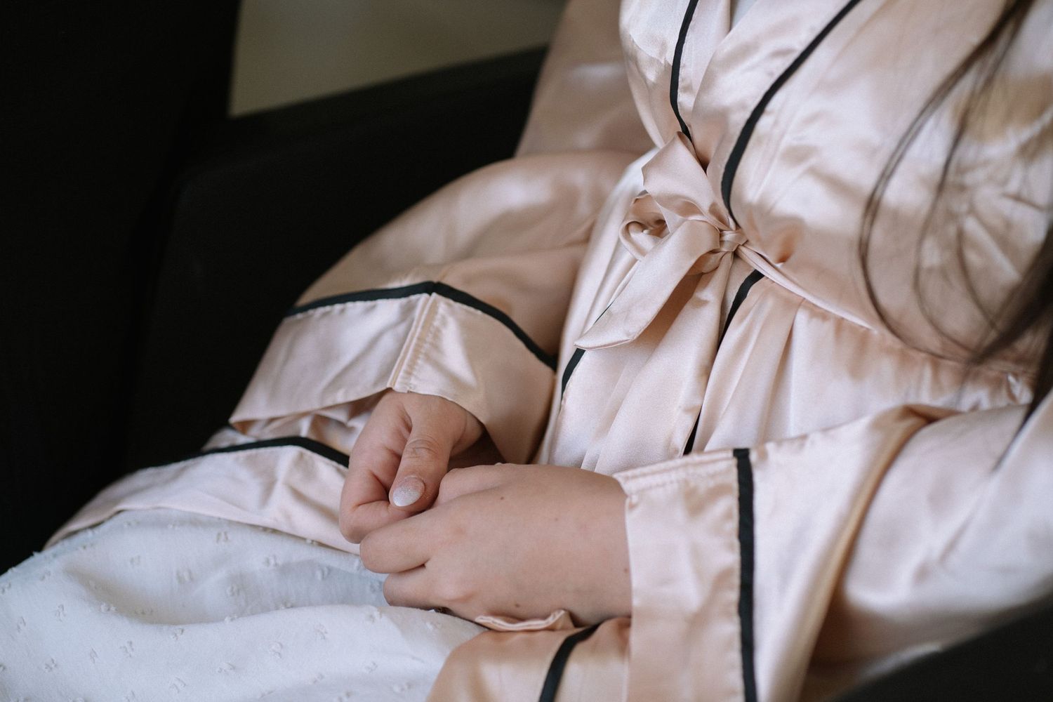 Close-up of hands resting on beige fabric in natural lighting.
