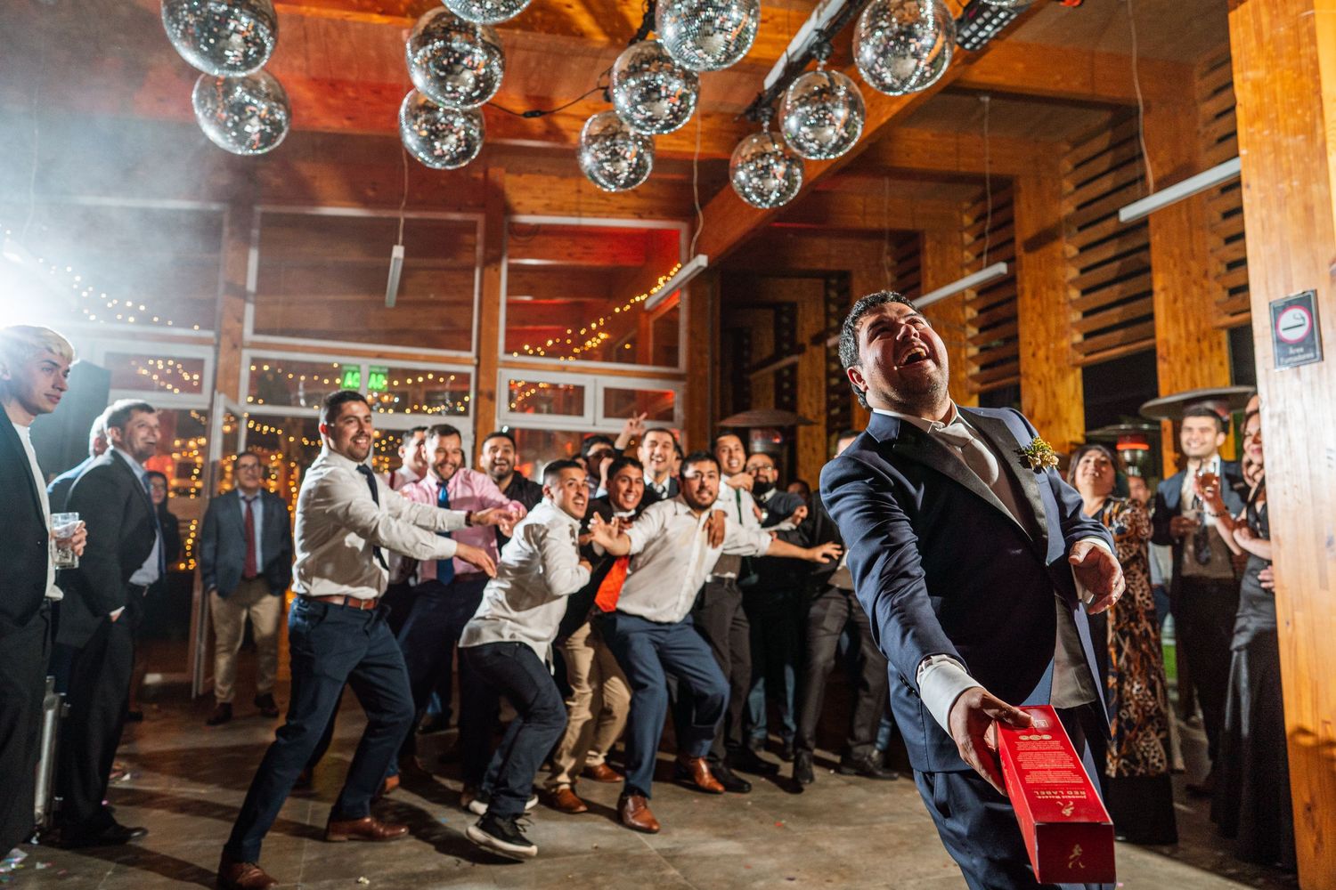 Wedding reception crowd dancing and celebrating under disco balls.