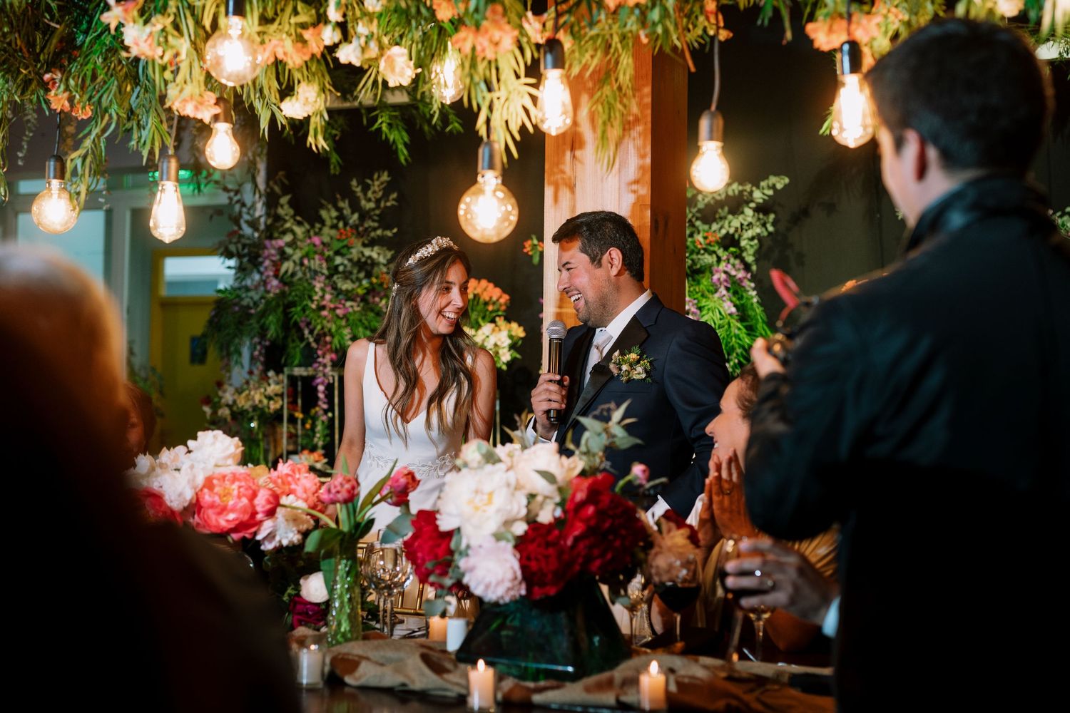 Wedding reception table with hanging lights, floral arrangements and romantic ambient lighting.