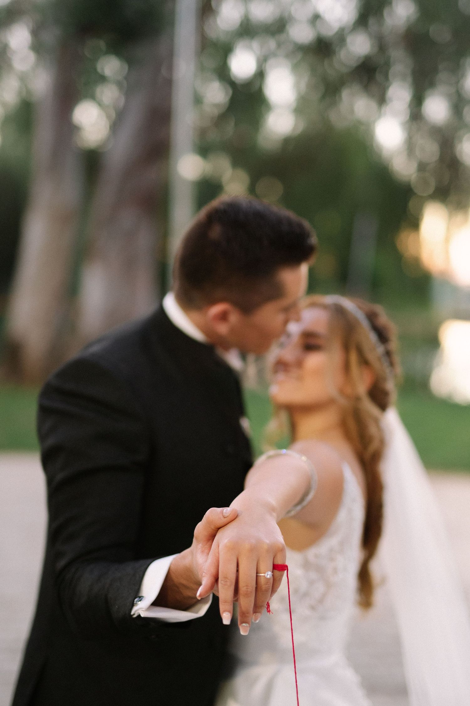 A romantic wedding photo showing a couple's ring while sharing an intimate moment outdoors.