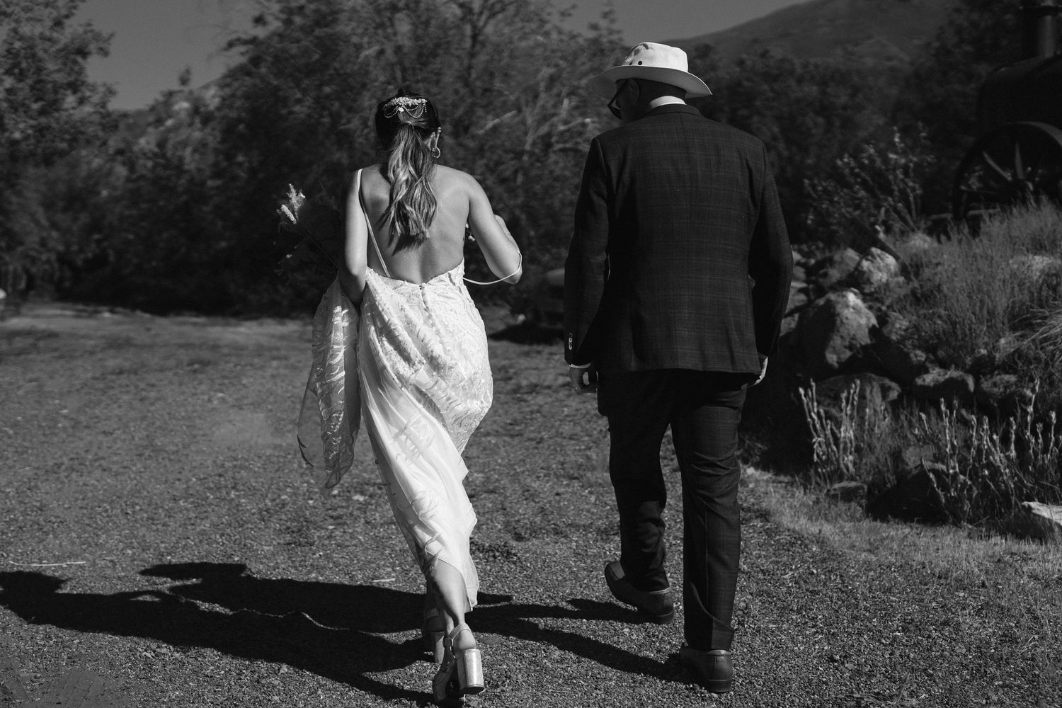 A black and white photo of a couple walking down a path in outdoor scenery.