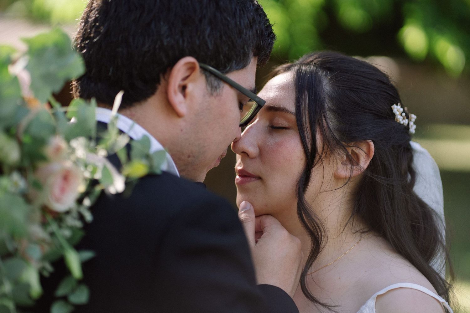 Intimate wedding portrait among blush-colored floral arrangements in a garden setting.