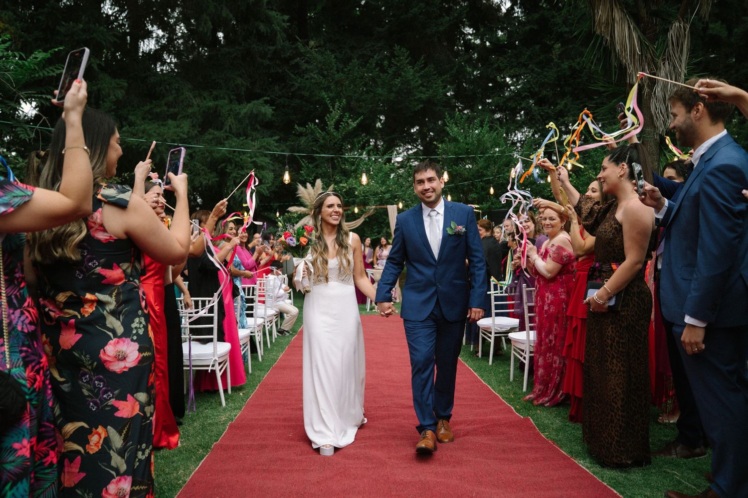 Wedding guests line both sides of a garden path creating a joyful exit tunnel for the newlyweds.