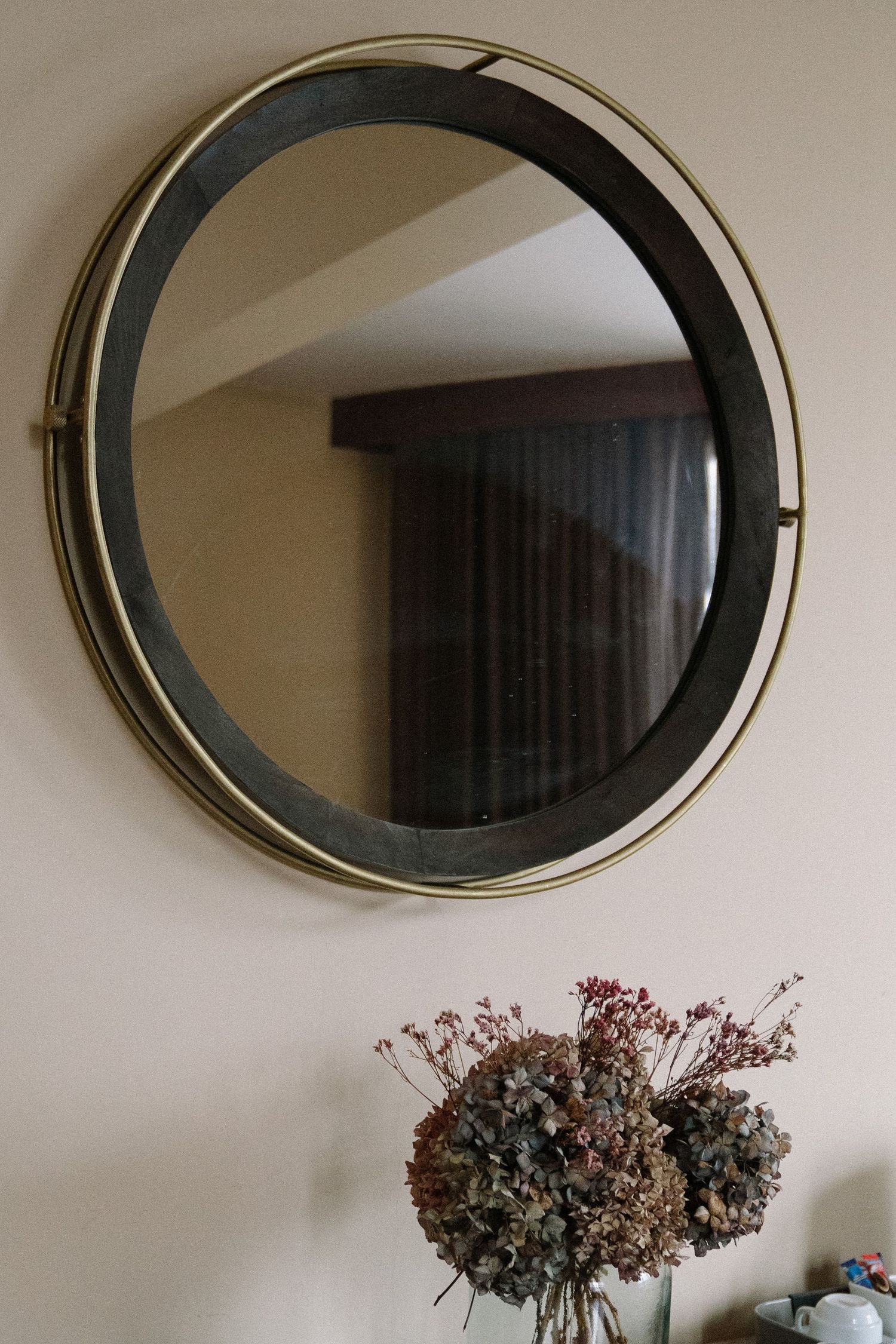 A row of four oval-shaped decorative mirrors with brass frames mounted on a beige wall.