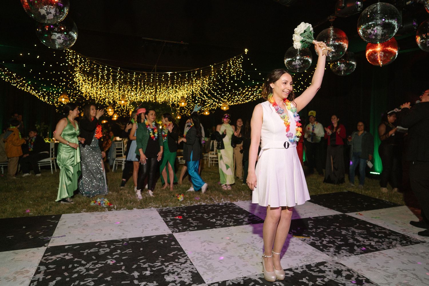 A celebratory moment on a black and white dance floor with string lights overhead.