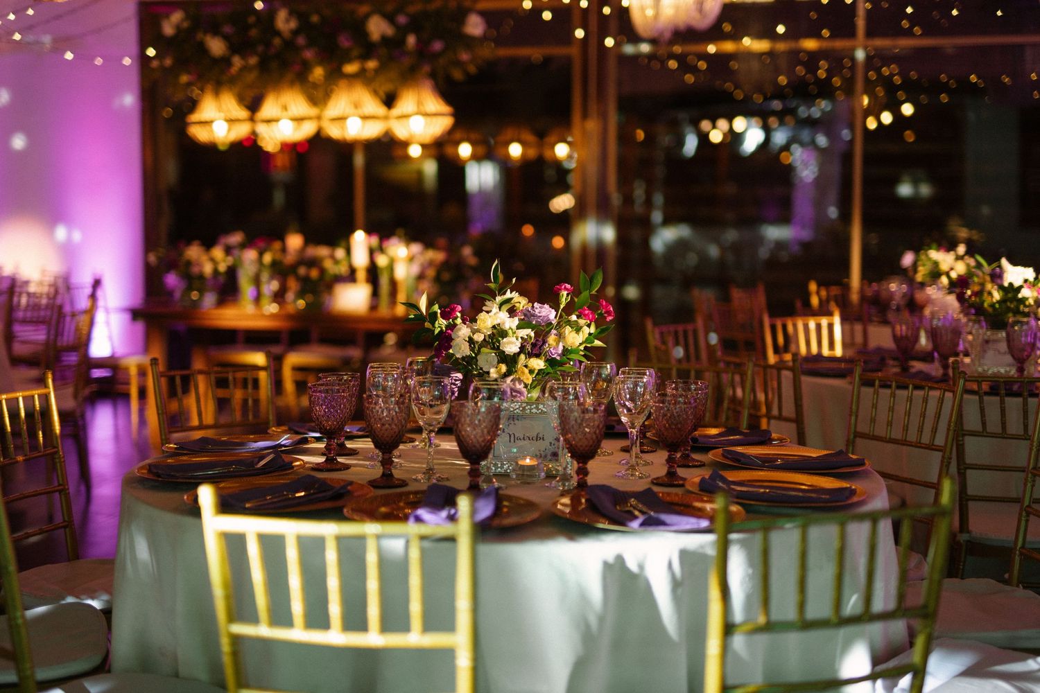 Elegant wedding reception table settings with gold chairs and ambient lighting creating romantic atmosphere.