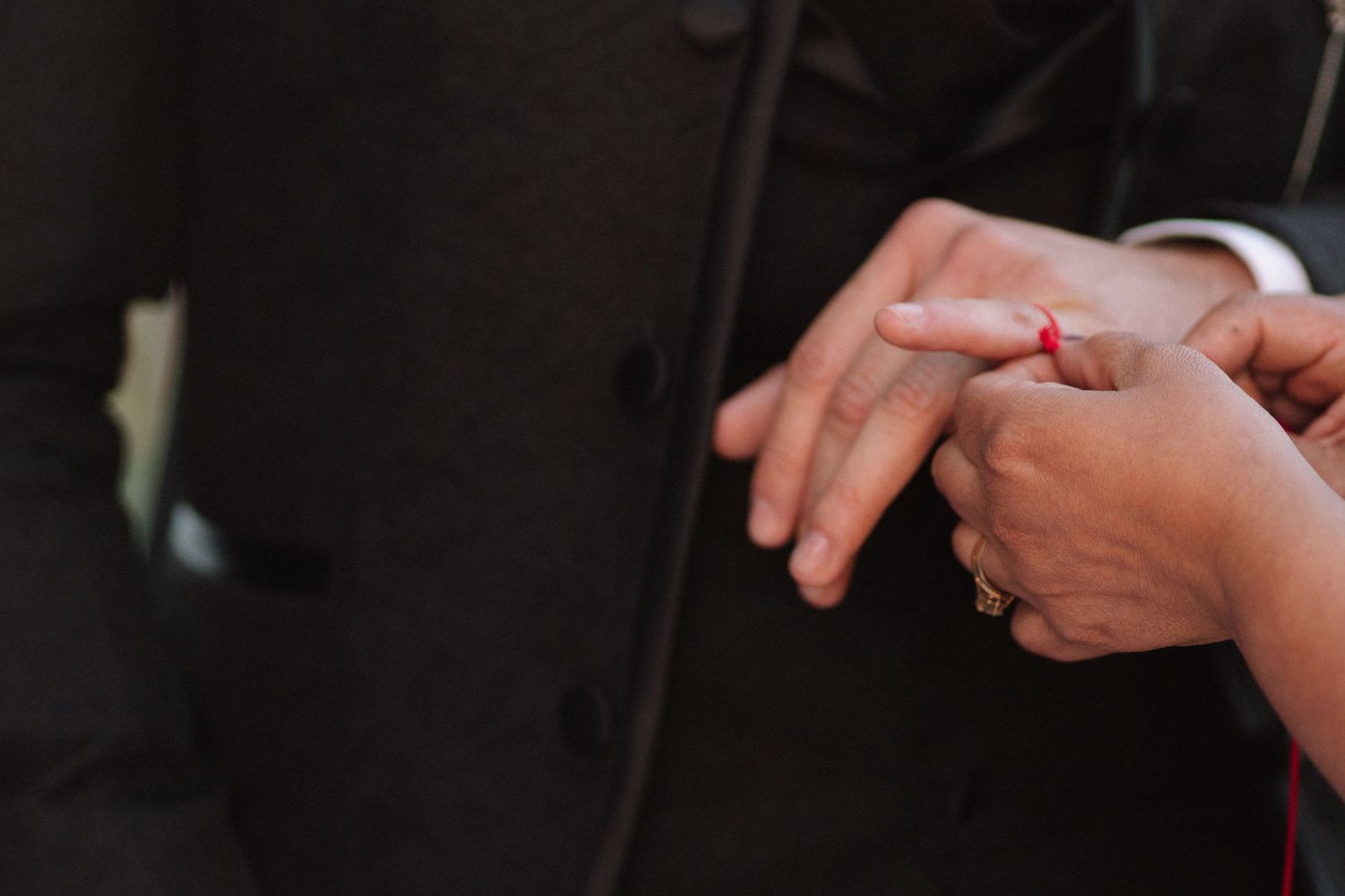 Close-up shot of hands exchanging wedding rings during ceremony.