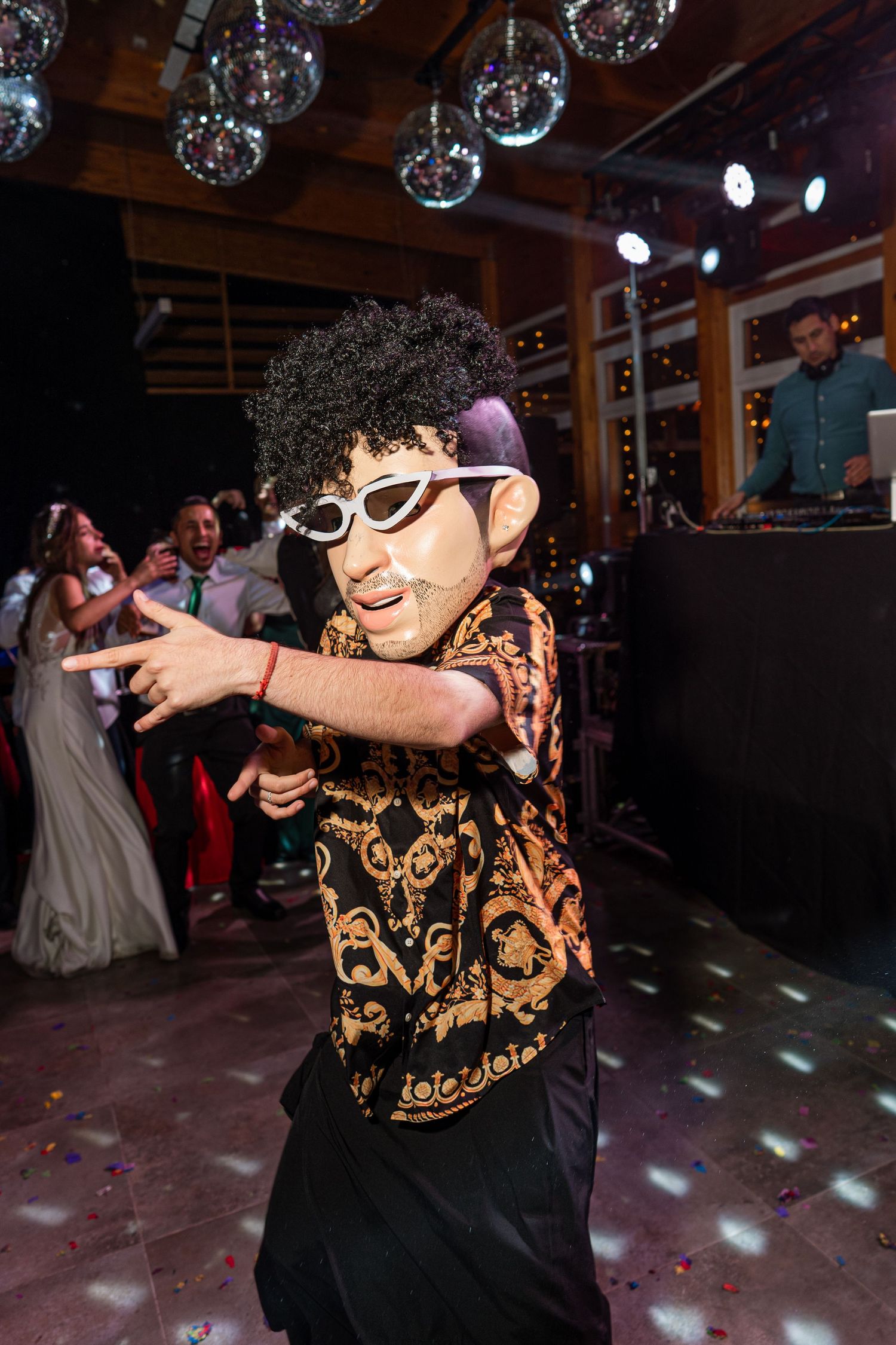 Young dancer in sunglasses and patterned shirt performing under disco balls.