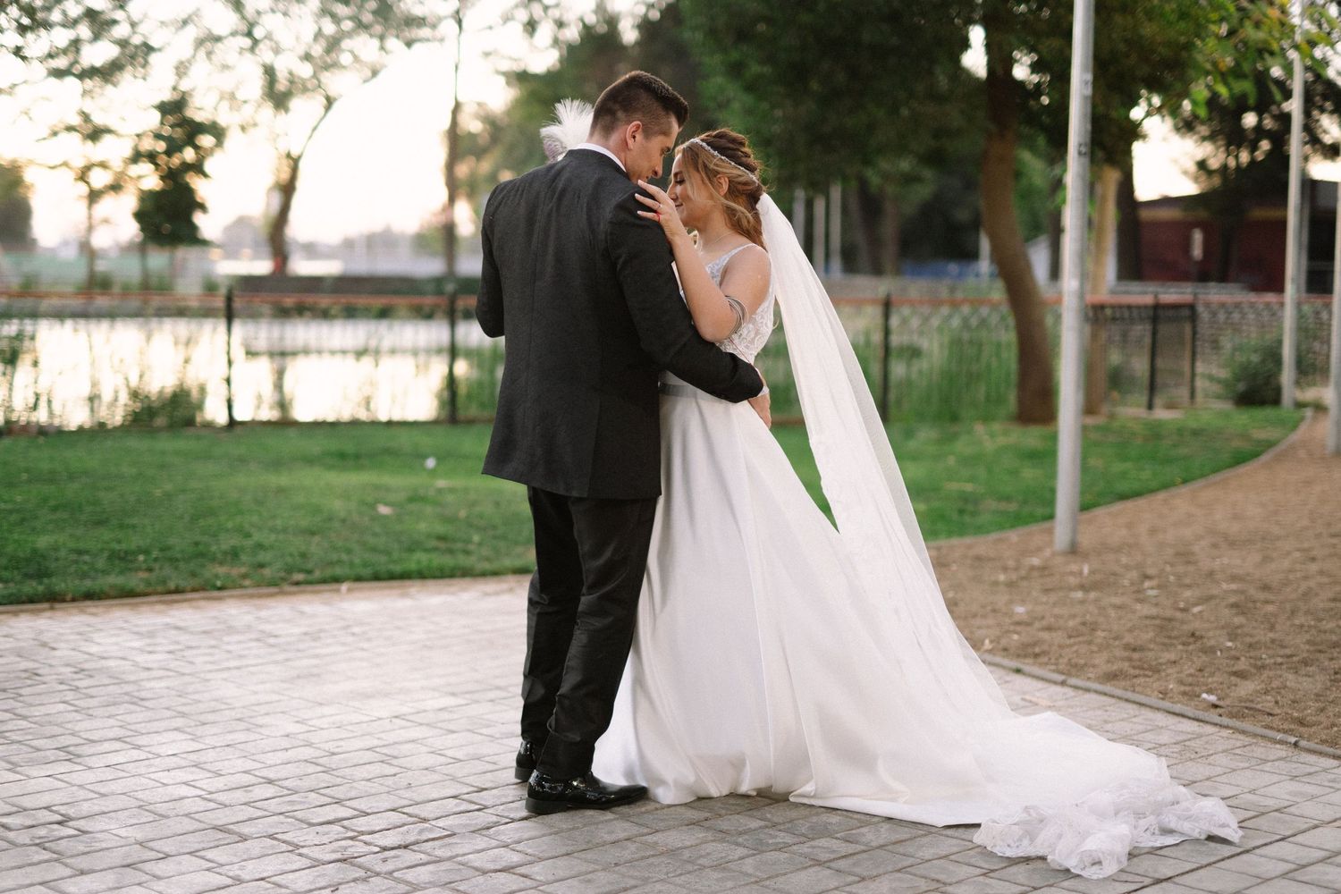 A wedding couple embraces while dancing on a stone pathway during sunset.