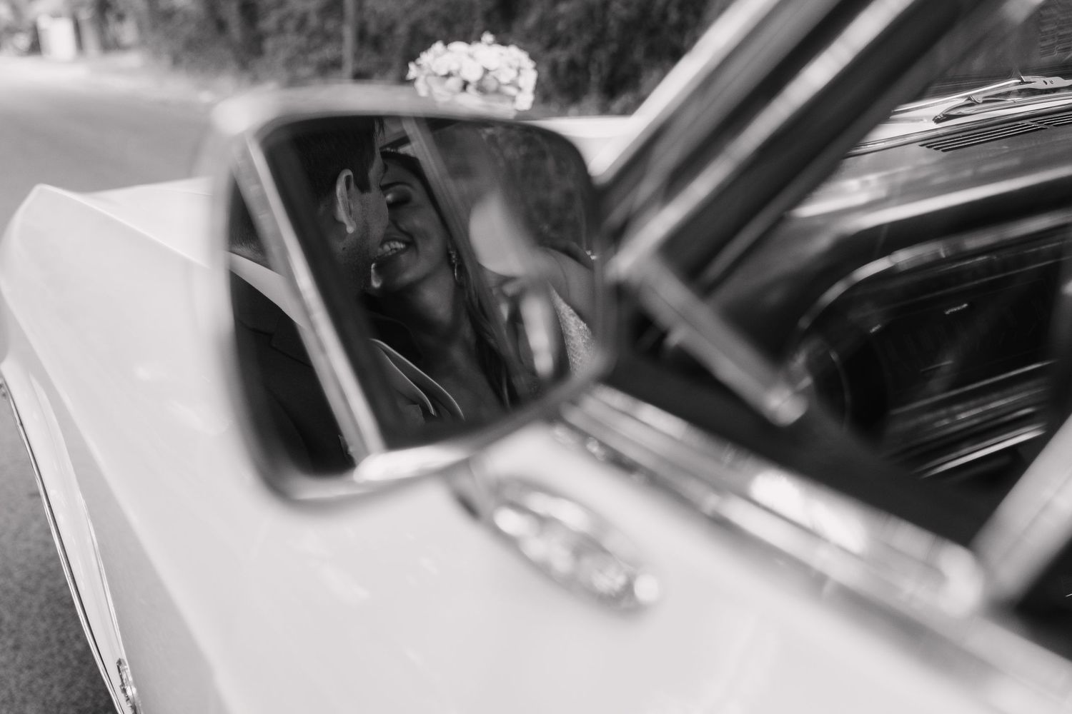 Black and white reflection of a bride in a car side mirror.