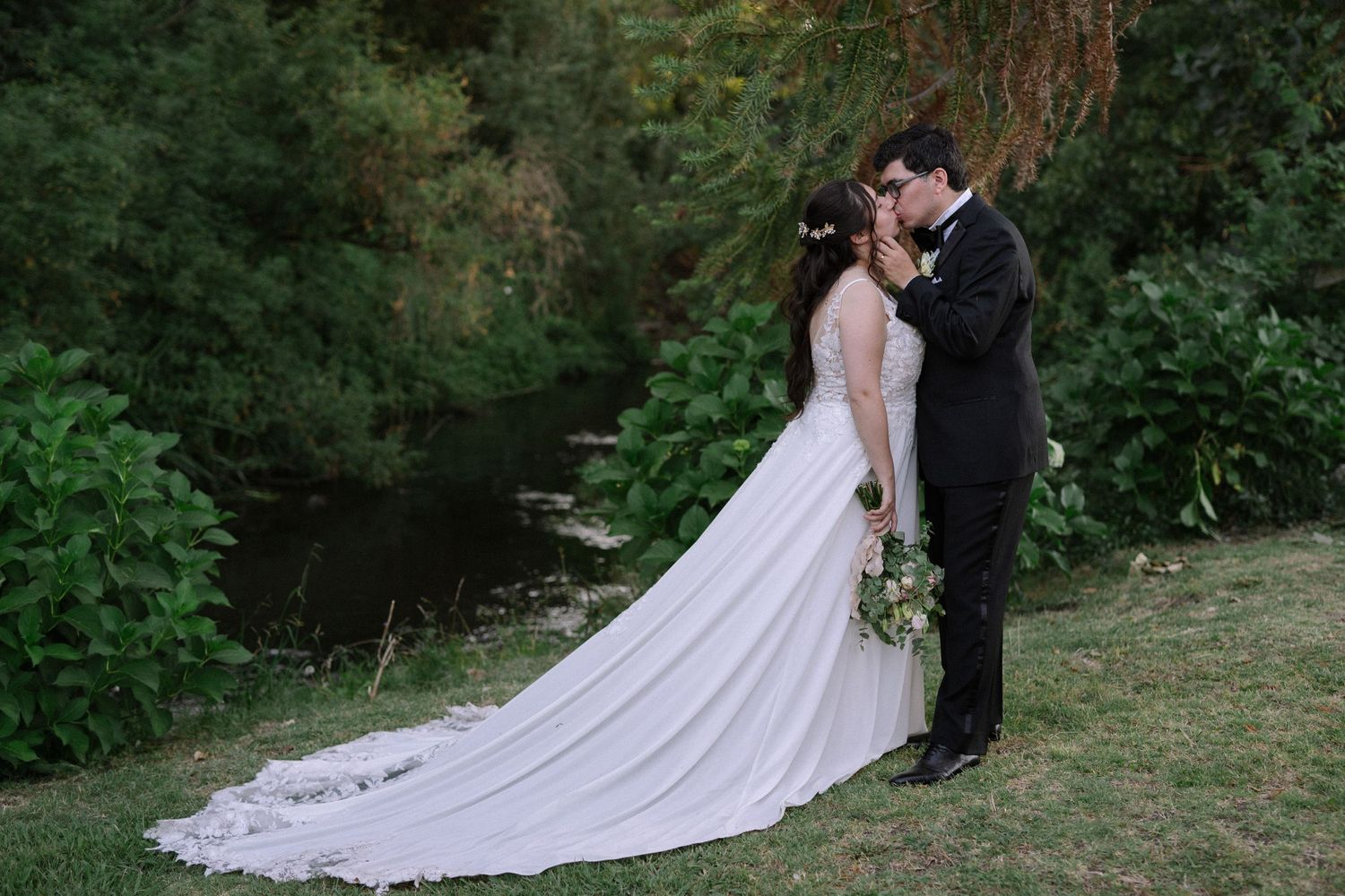 A tender wedding moment photographed against a backdrop of evergreen trees.