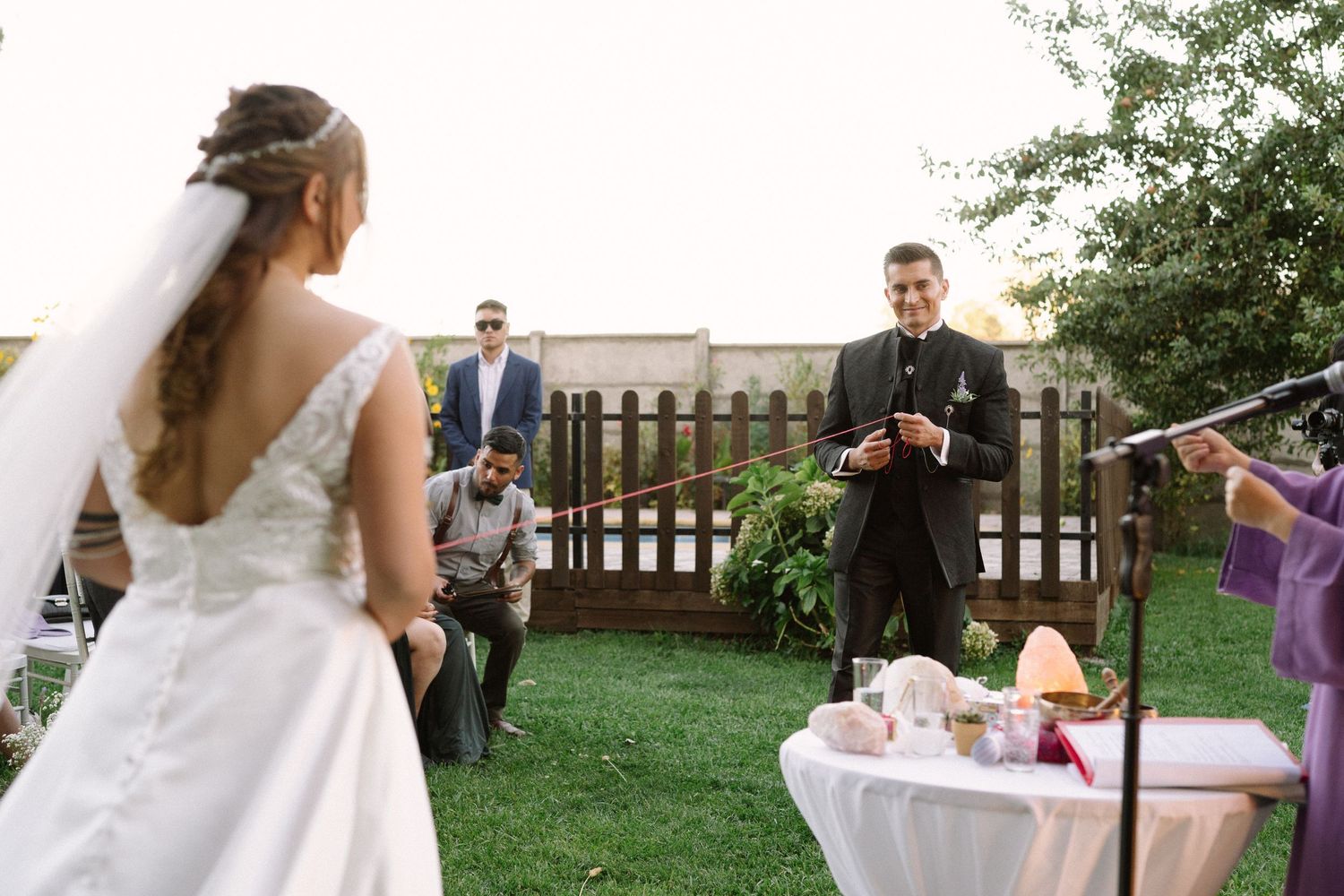 Outdoor wedding ceremony scene with decorated altar and guests on lawn.