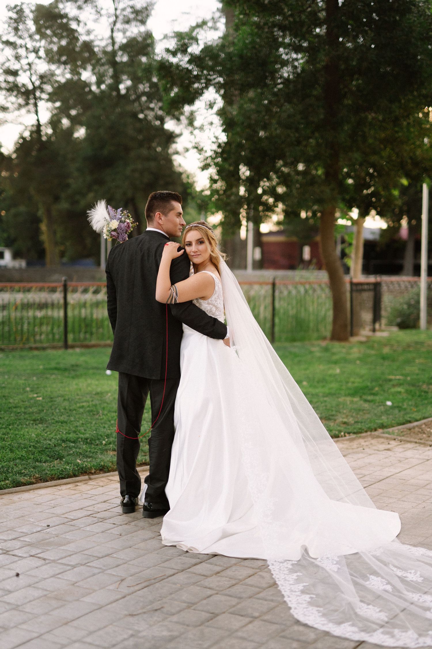 An intimate wedding portrait on a paved pathway with lush greenery in the background.