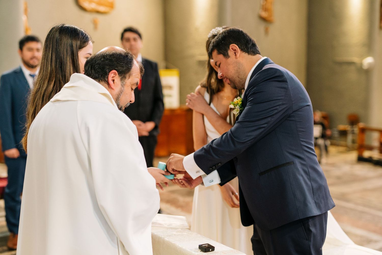 A wedding ceremony moment as couple exchanges vows with priest officiating.