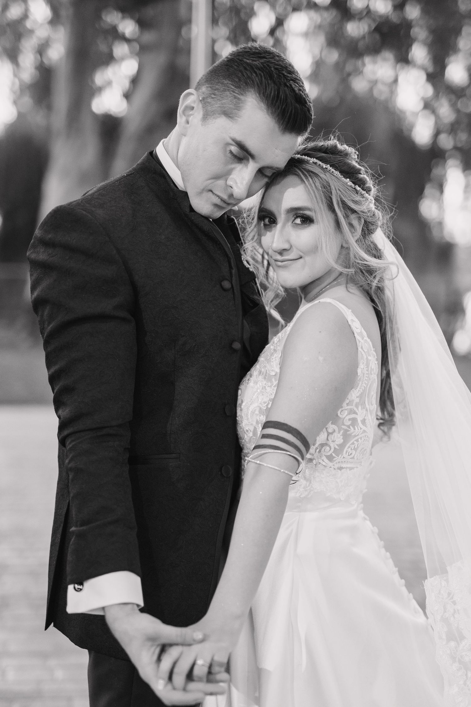 A romantic black and white portrait of newlyweds embracing outdoors.