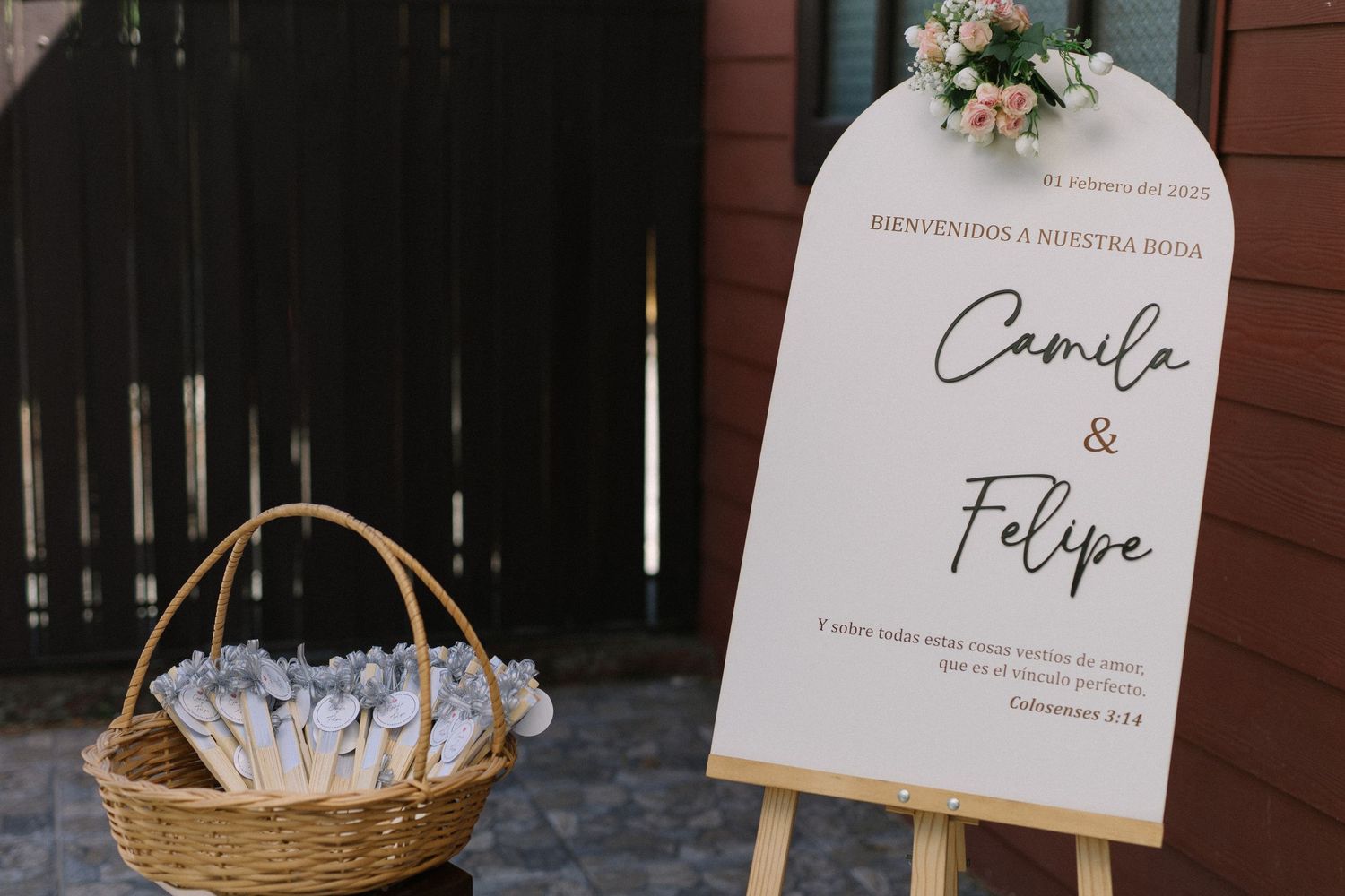 Wedding welcome sign for Camila and Felipe displayed on easel with basket of favors.