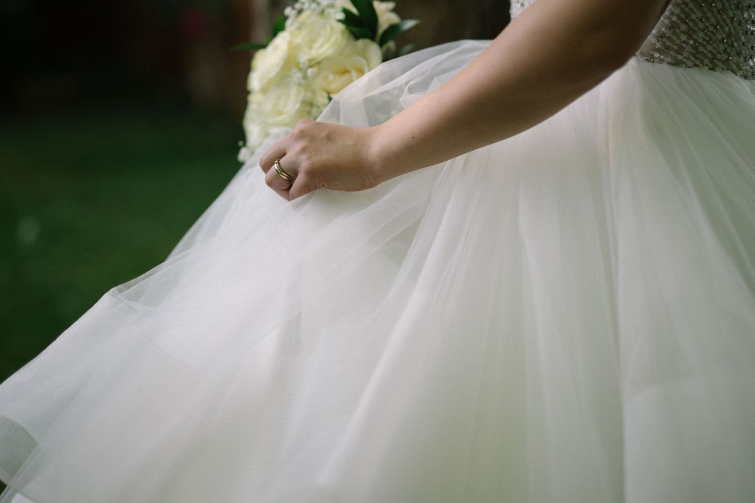 Detail shot of white tulle wedding dress fabric against green background.