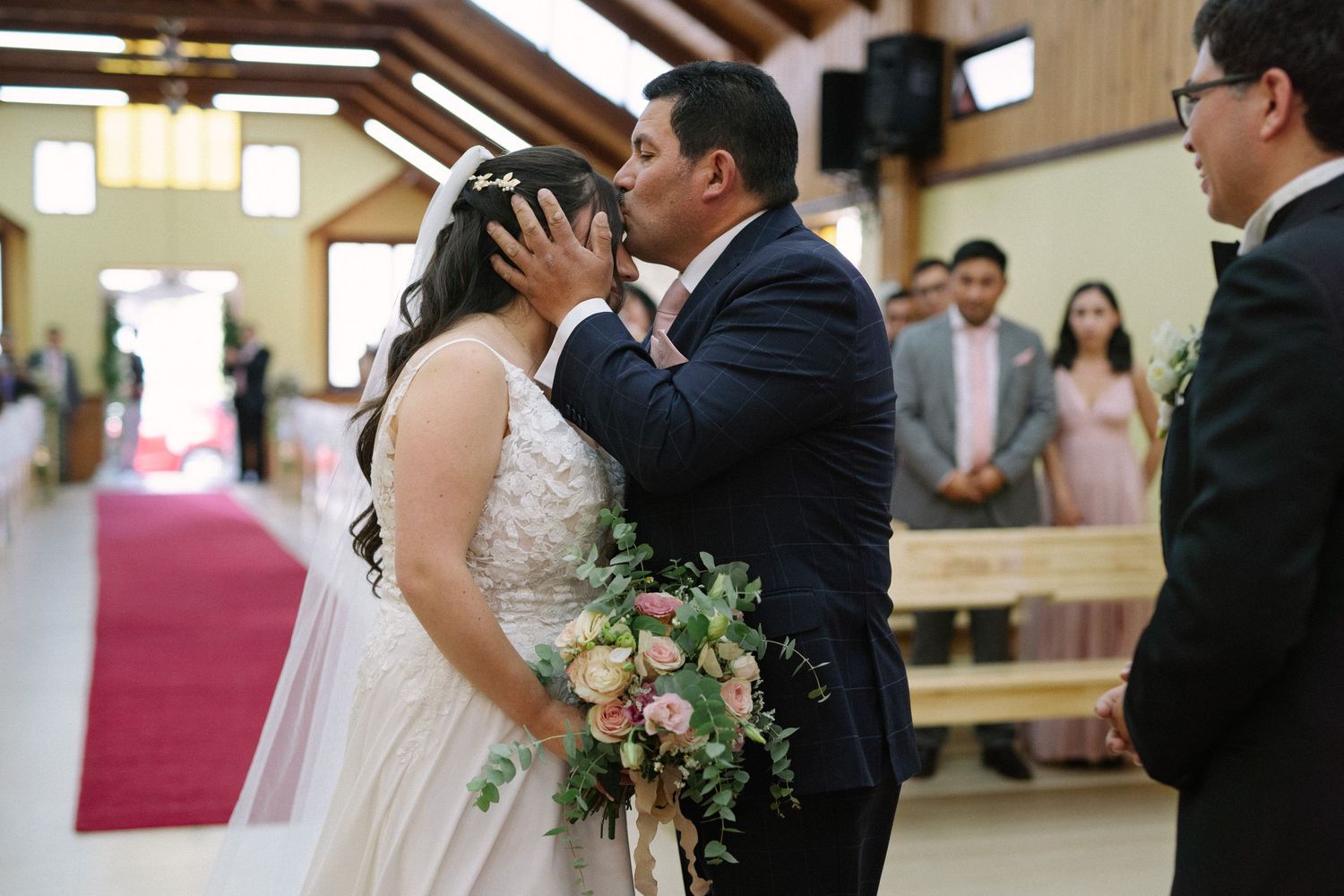 A tender moment between newlyweds during their church wedding ceremony with bouquet details.