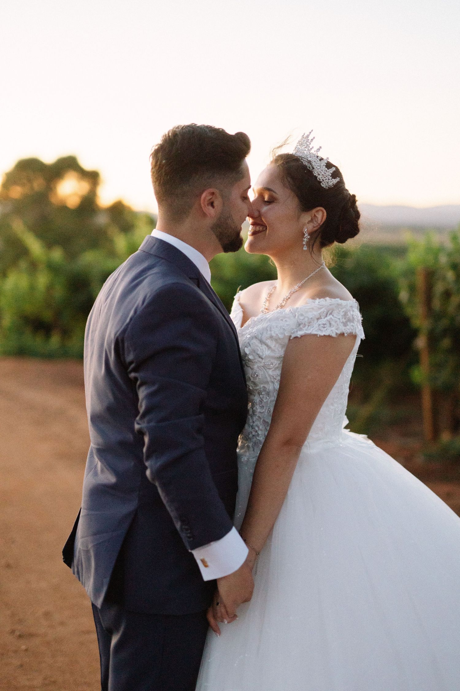 A romantic sunset moment between newlyweds in a vineyard setting.
