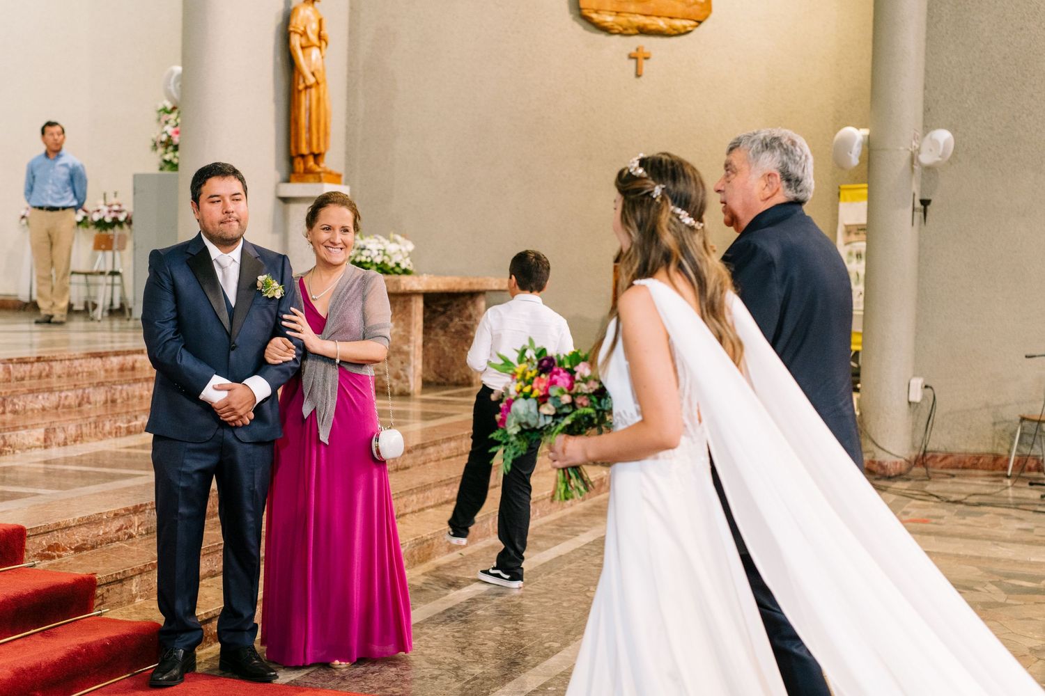 A wedding ceremony moment with attendants in formal attire inside a church.