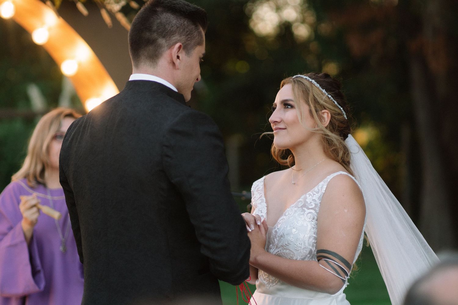 A couple engages in heartfelt exchange during their wedding ceremony beneath a decorative arch.