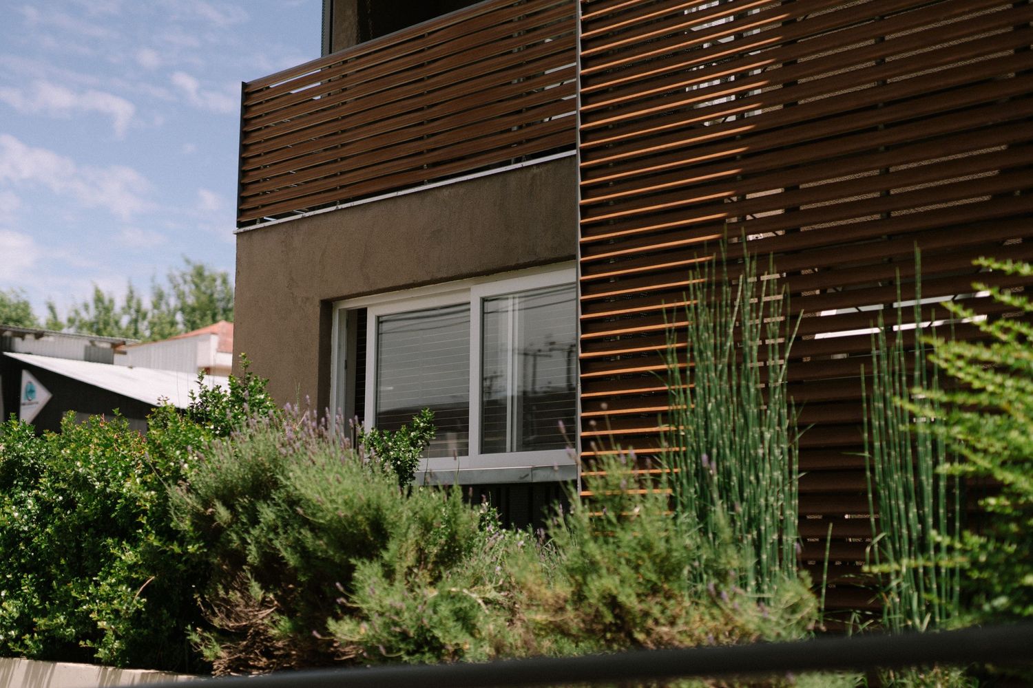 Modern architectural detail with wood slat siding and landscaped garden.