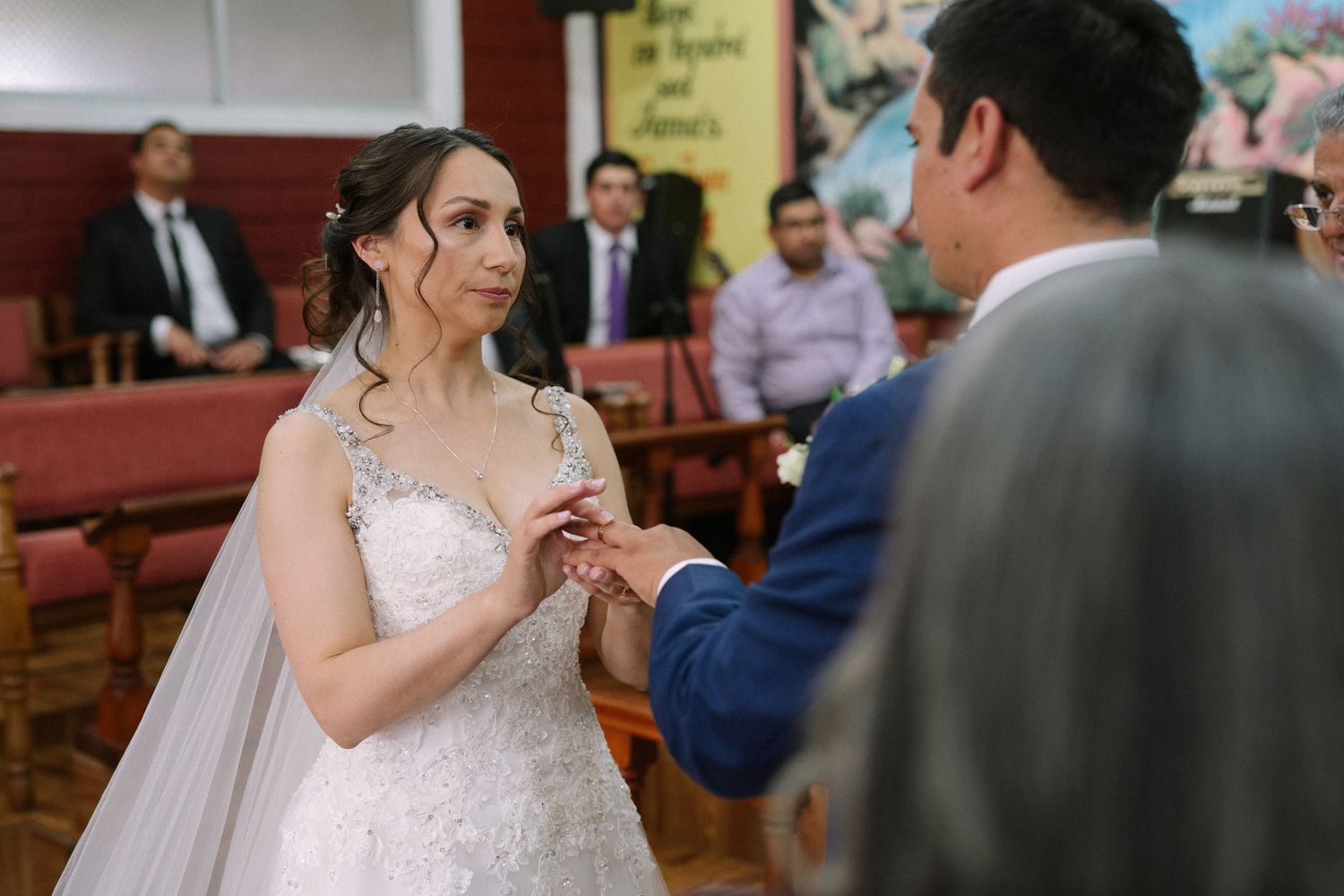 Close-up of ring exchange during wedding ceremony in brick-walled venue.