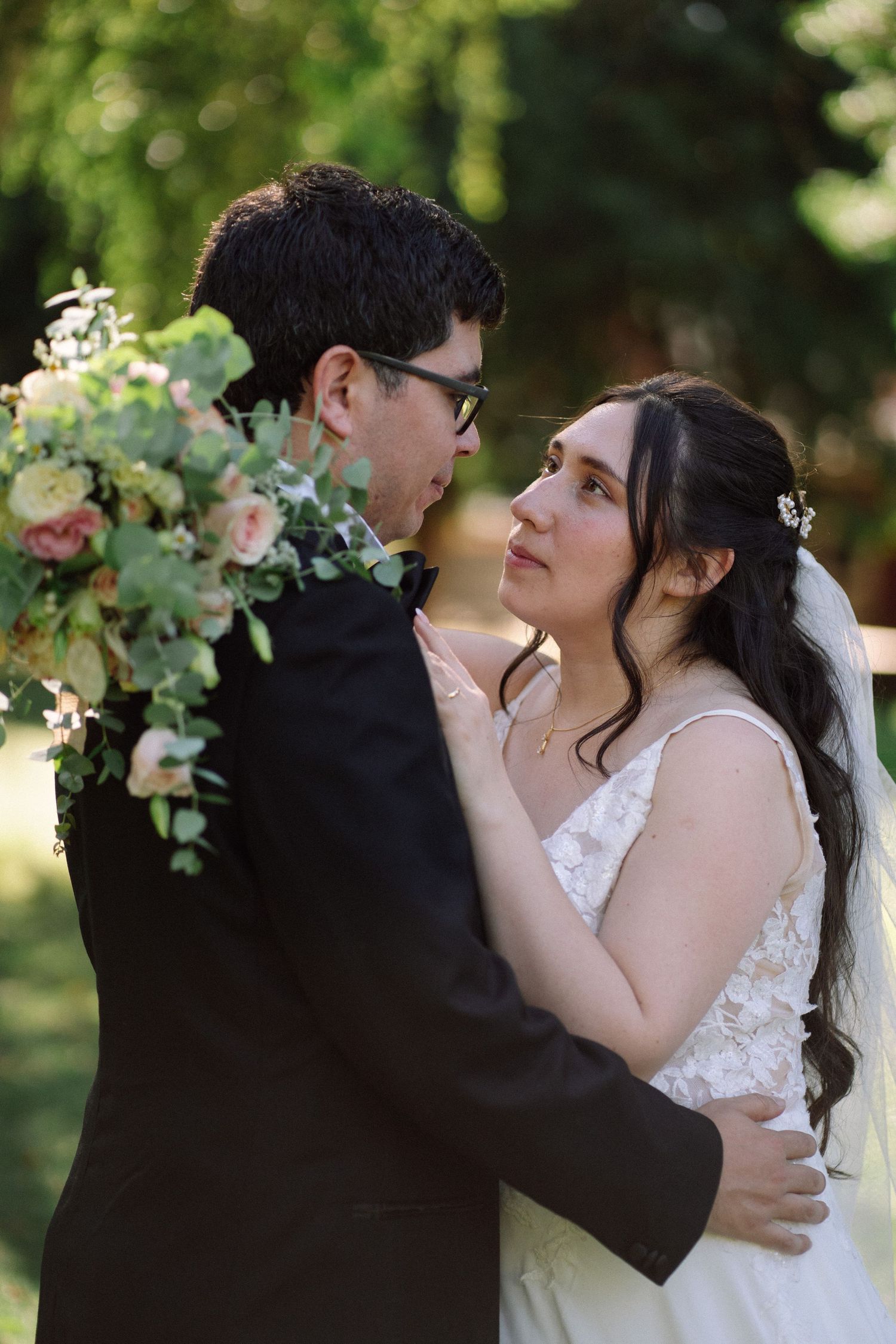 A tender embrace between newlyweds surrounded by delicate floral arrangements in a garden setting.